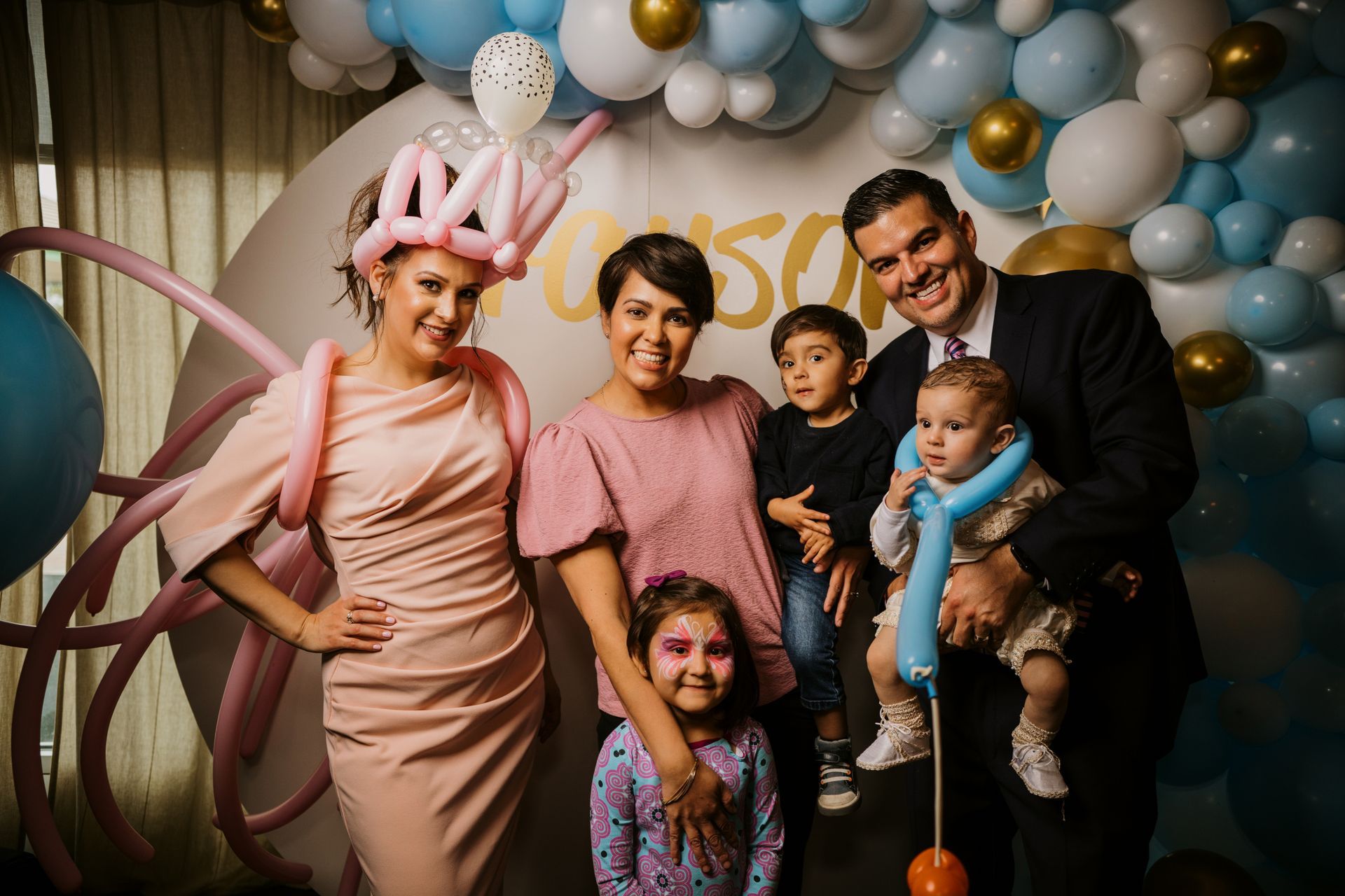 A family is posing for a picture in front of balloons.