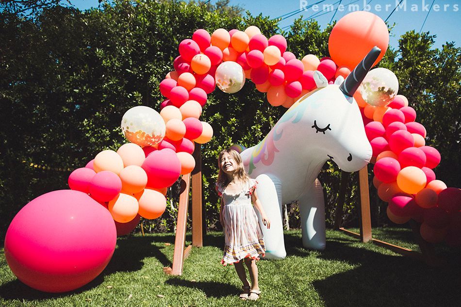 A little girl is standing in front of an inflatable unicorn