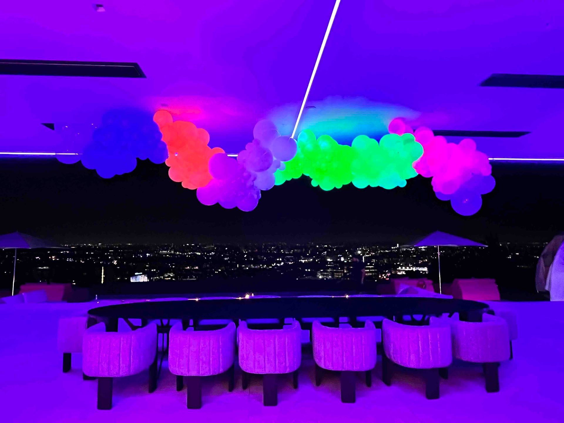 A room with a table and chairs and balloons hanging from the ceiling