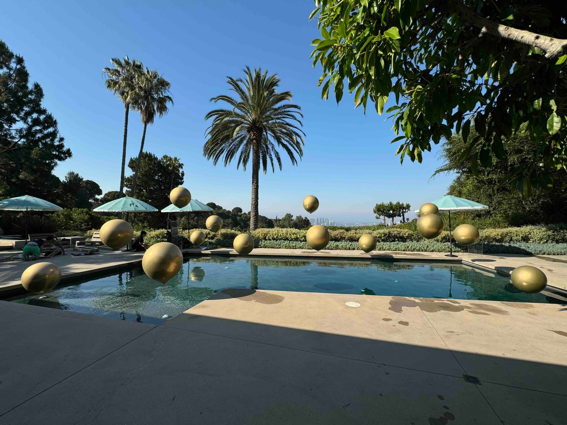 A swimming pool surrounded by palm trees and umbrellas