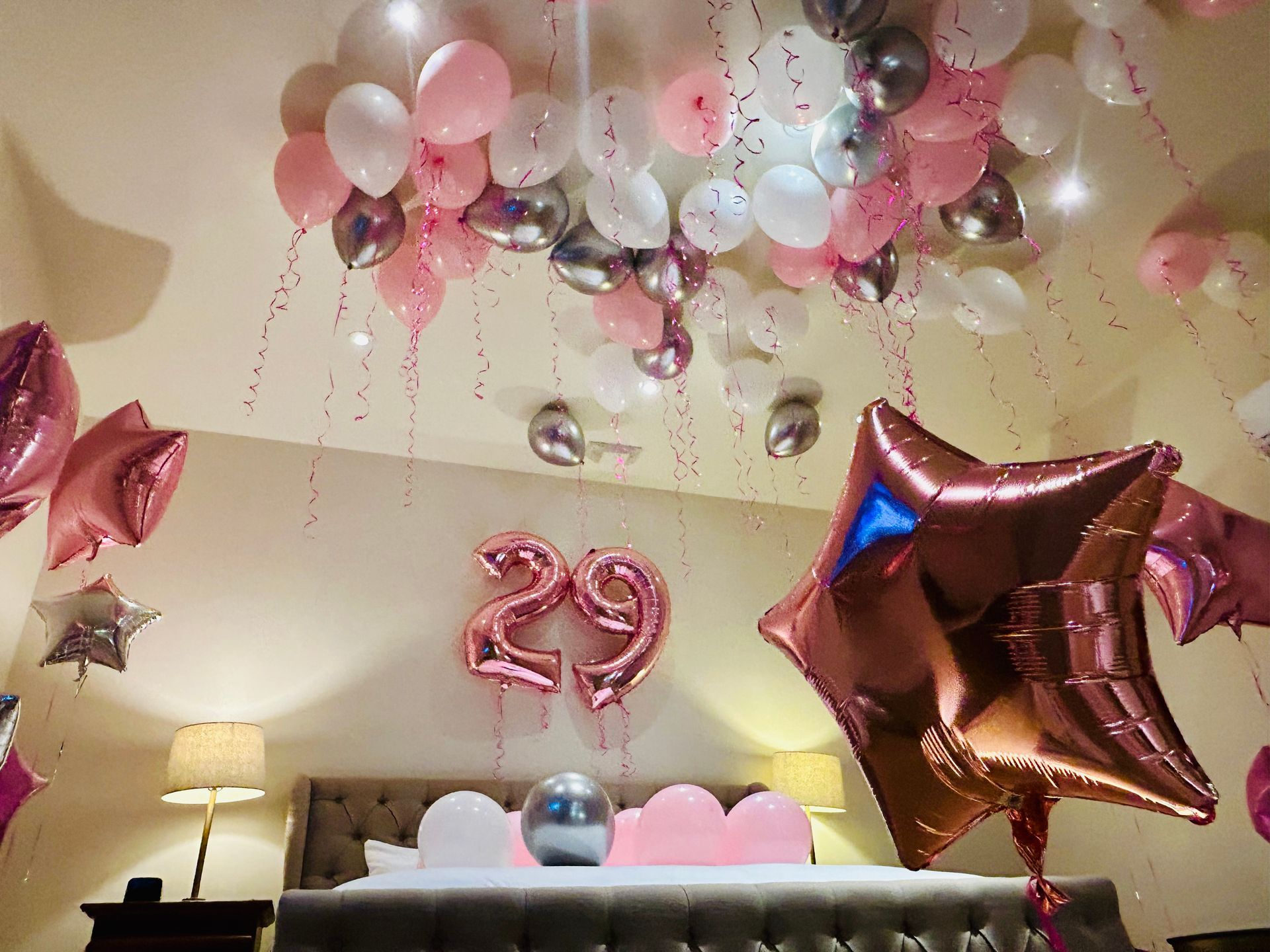 A bedroom decorated with balloons and the number 29 on the ceiling.
