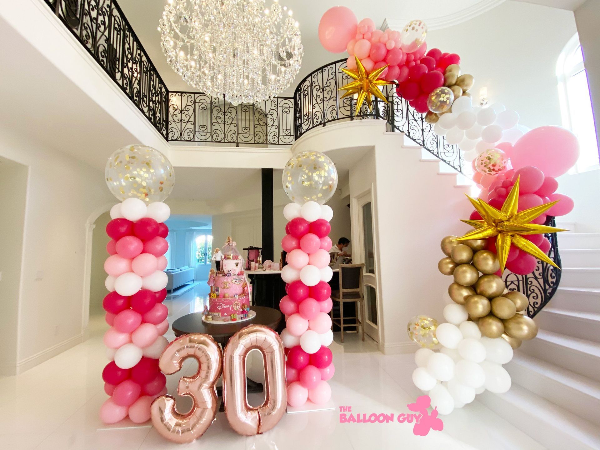 A room decorated with balloons and a cake for a 30th birthday.