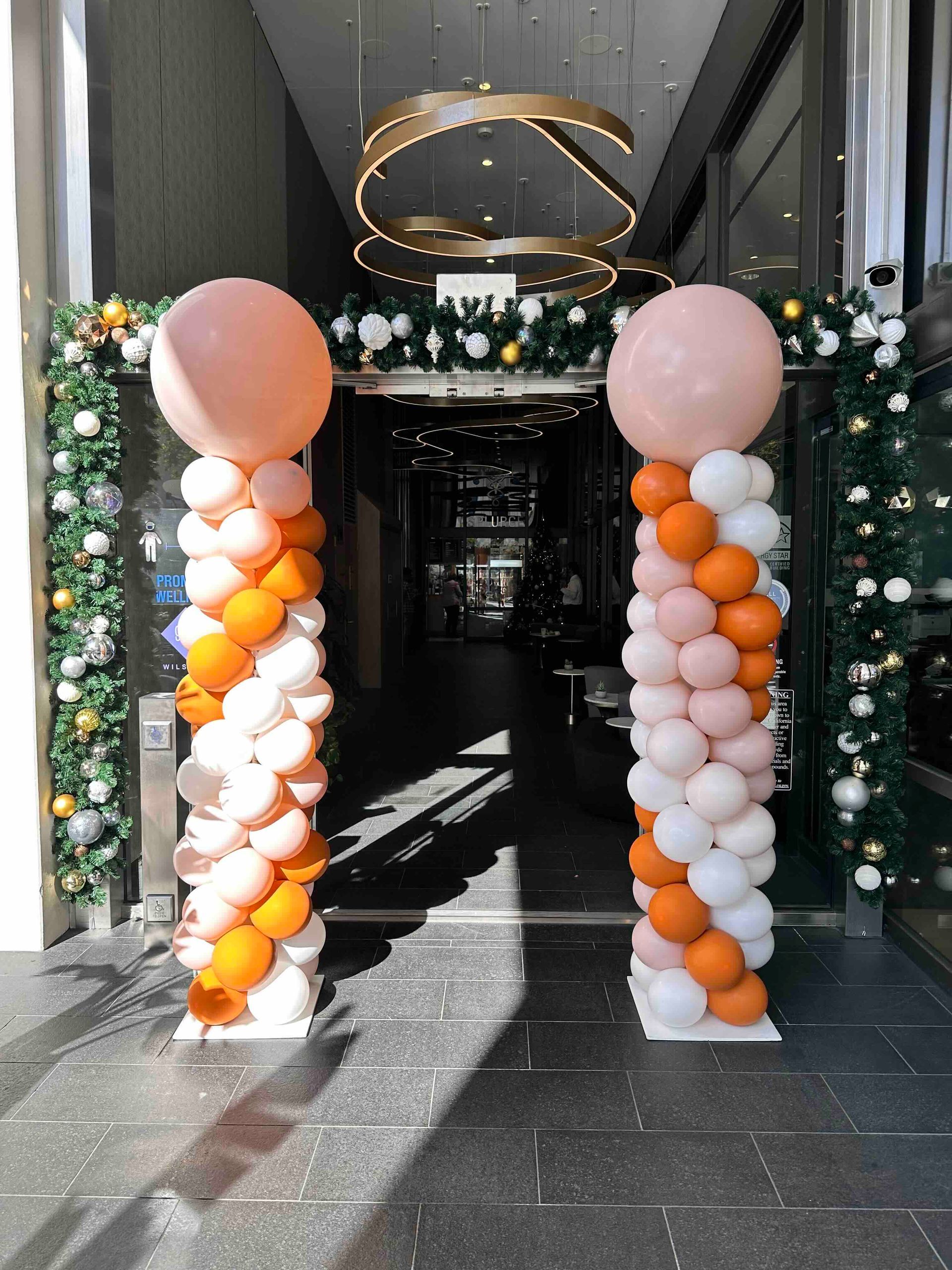A row of balloons are lined up in front of an office building. Balloon deliveries for business.