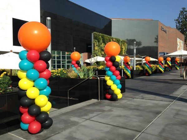 A row of colorful balloons are lined up in front of a building
