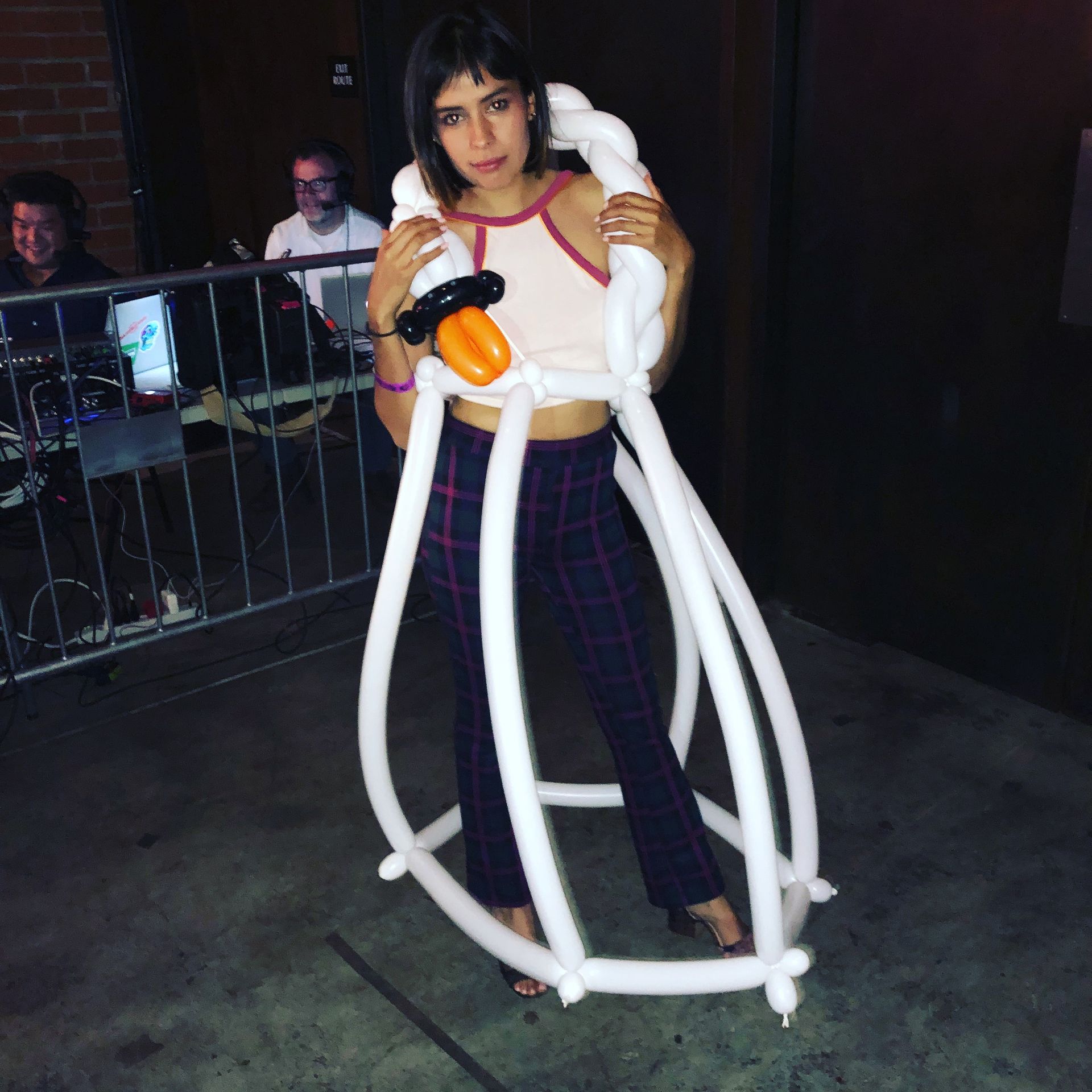A woman is standing in front of a fence holding balloons