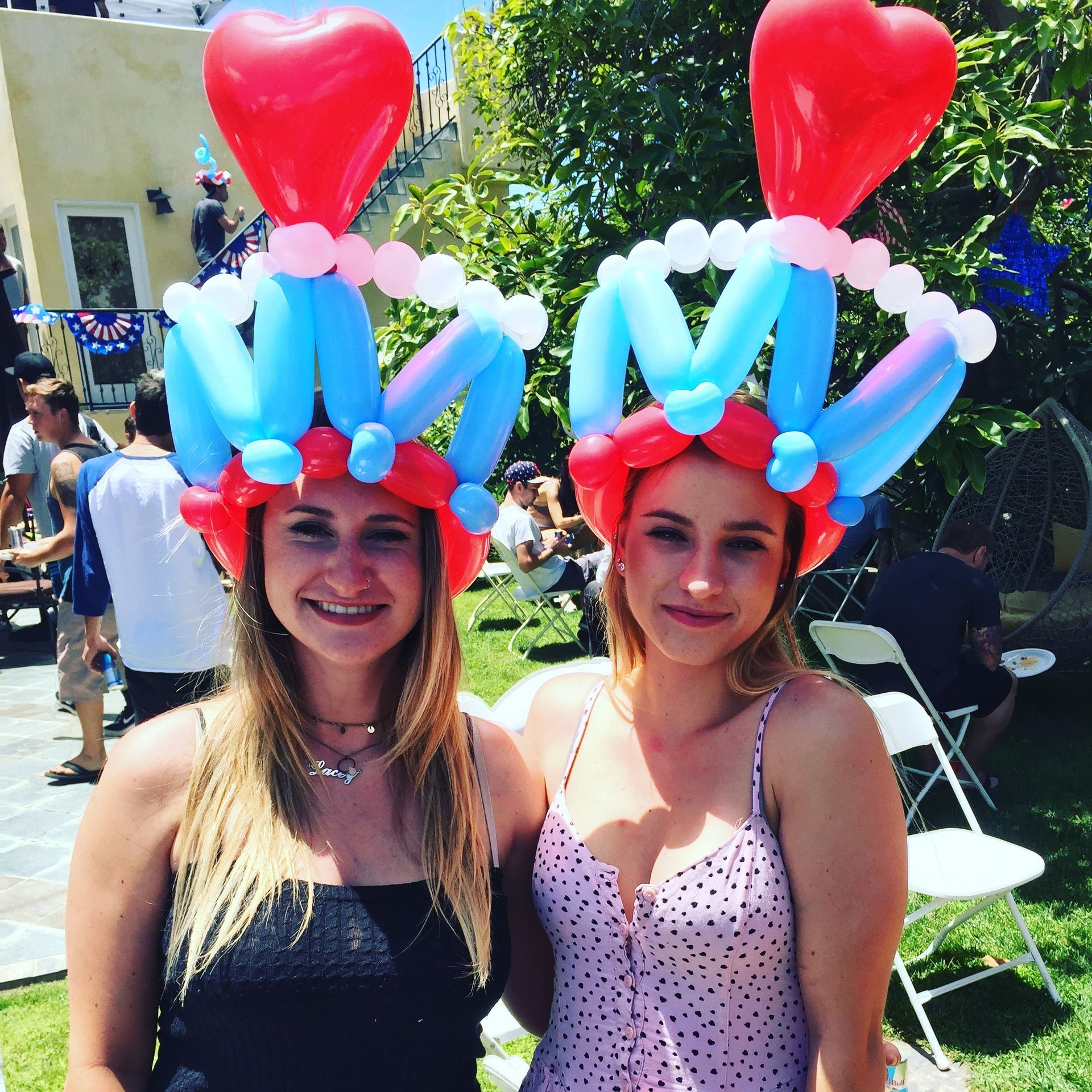 Two women wearing balloon hats with the letter m on them