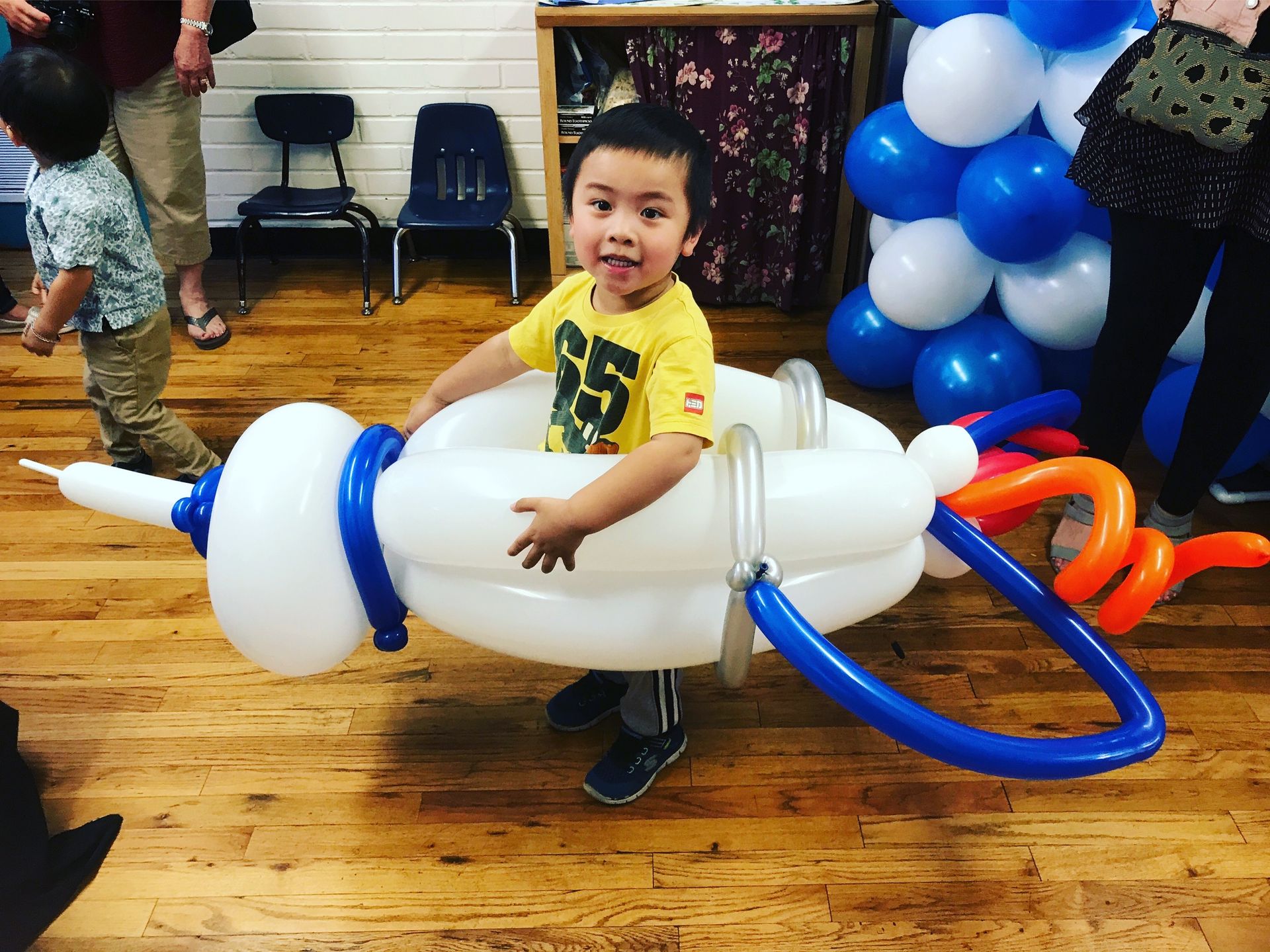 A young boy is standing next to a balloon airplane.