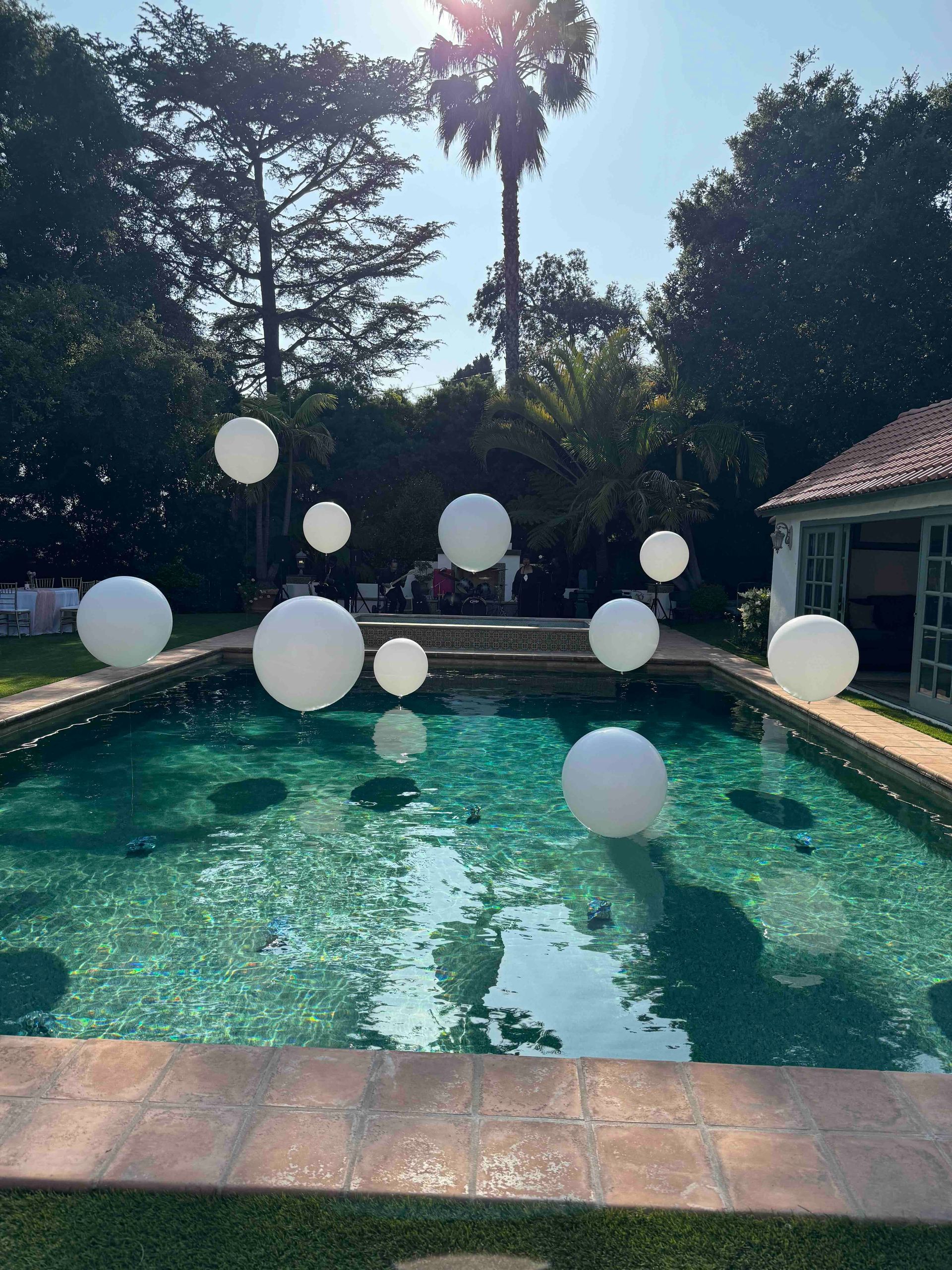 A swimming pool filled with white balloons on a sunny day