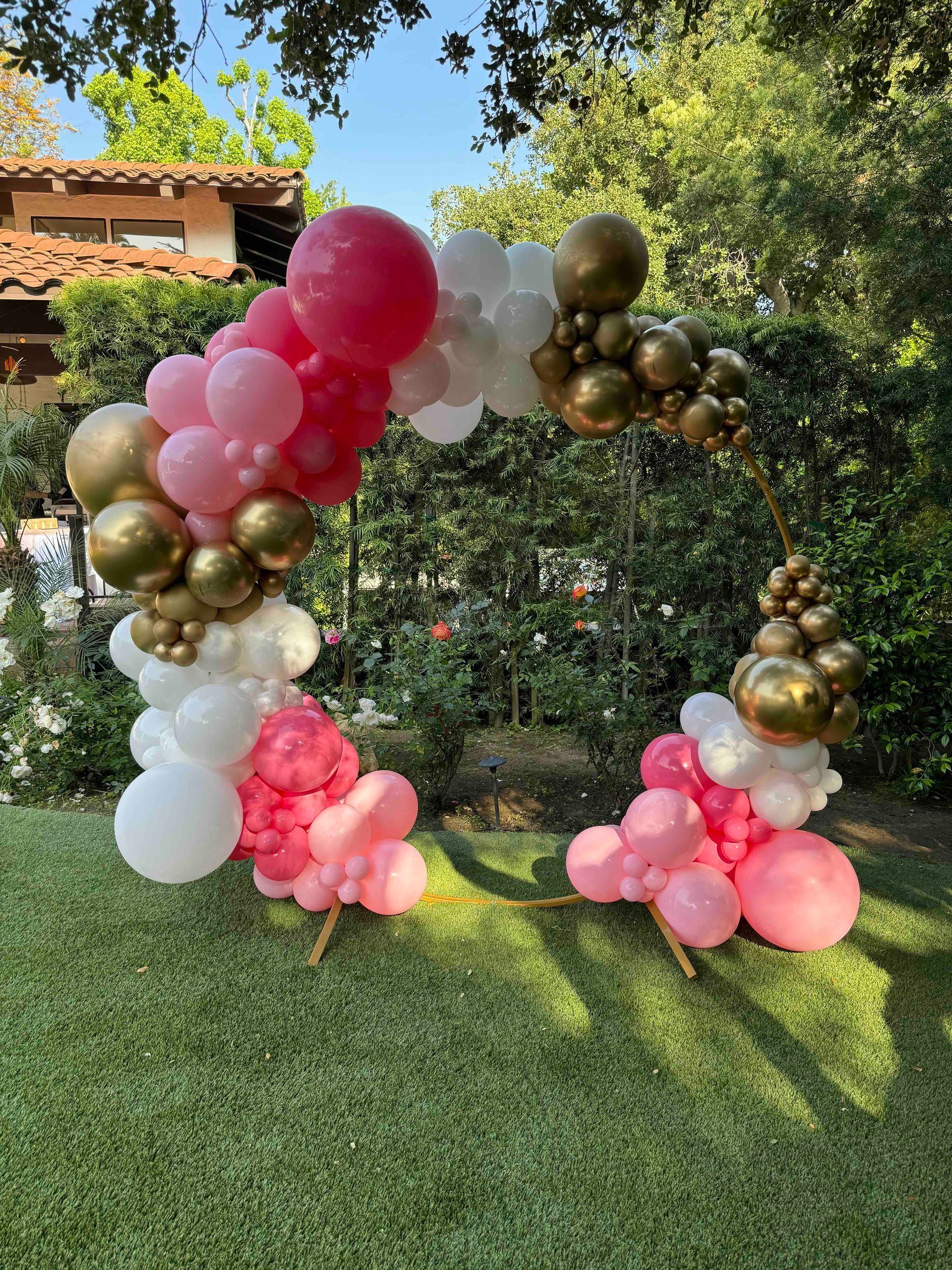A balloon arch is sitting on top of a lush green field.