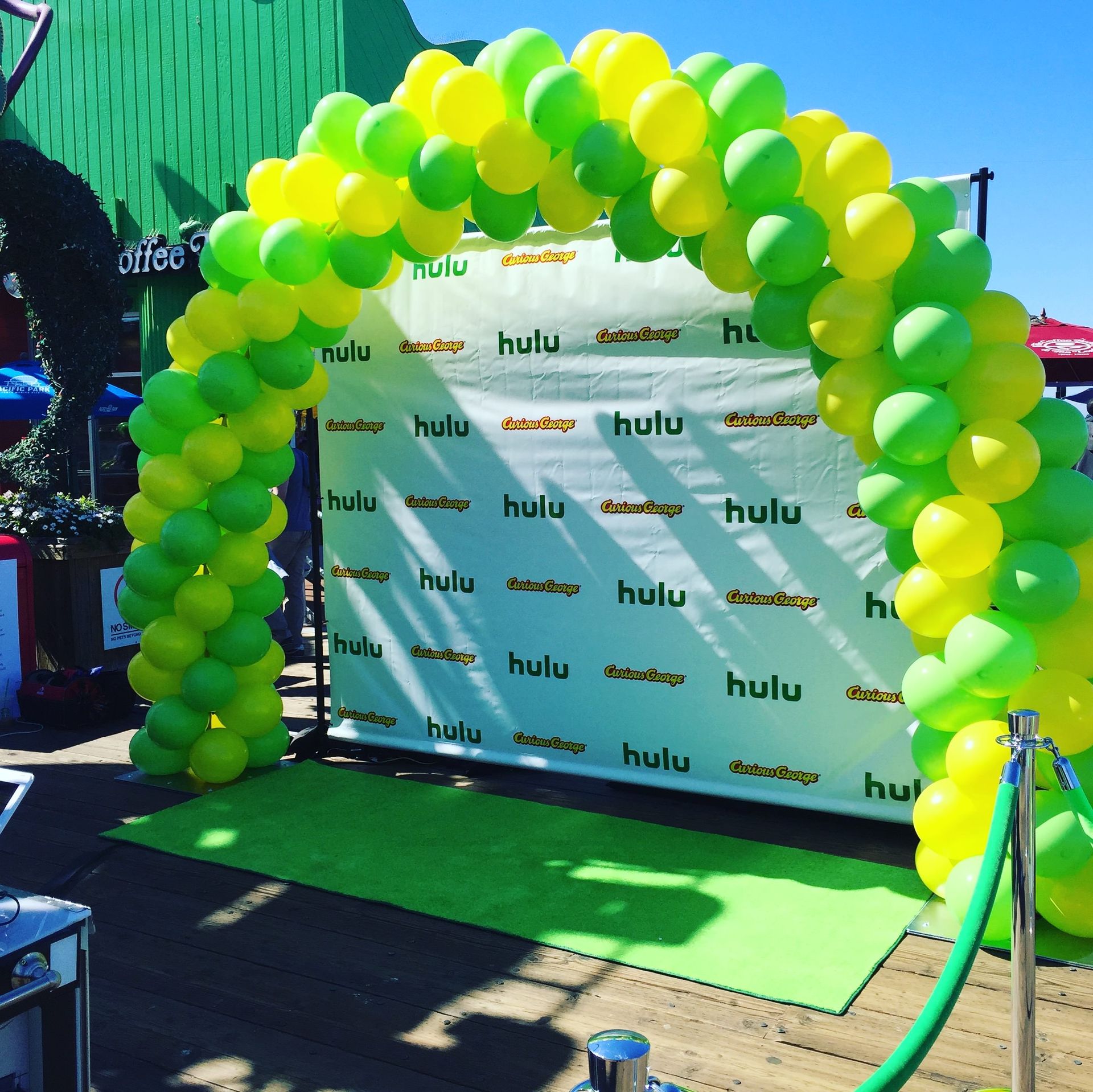 A green and yellow balloon arch in front of a sign that says hulu