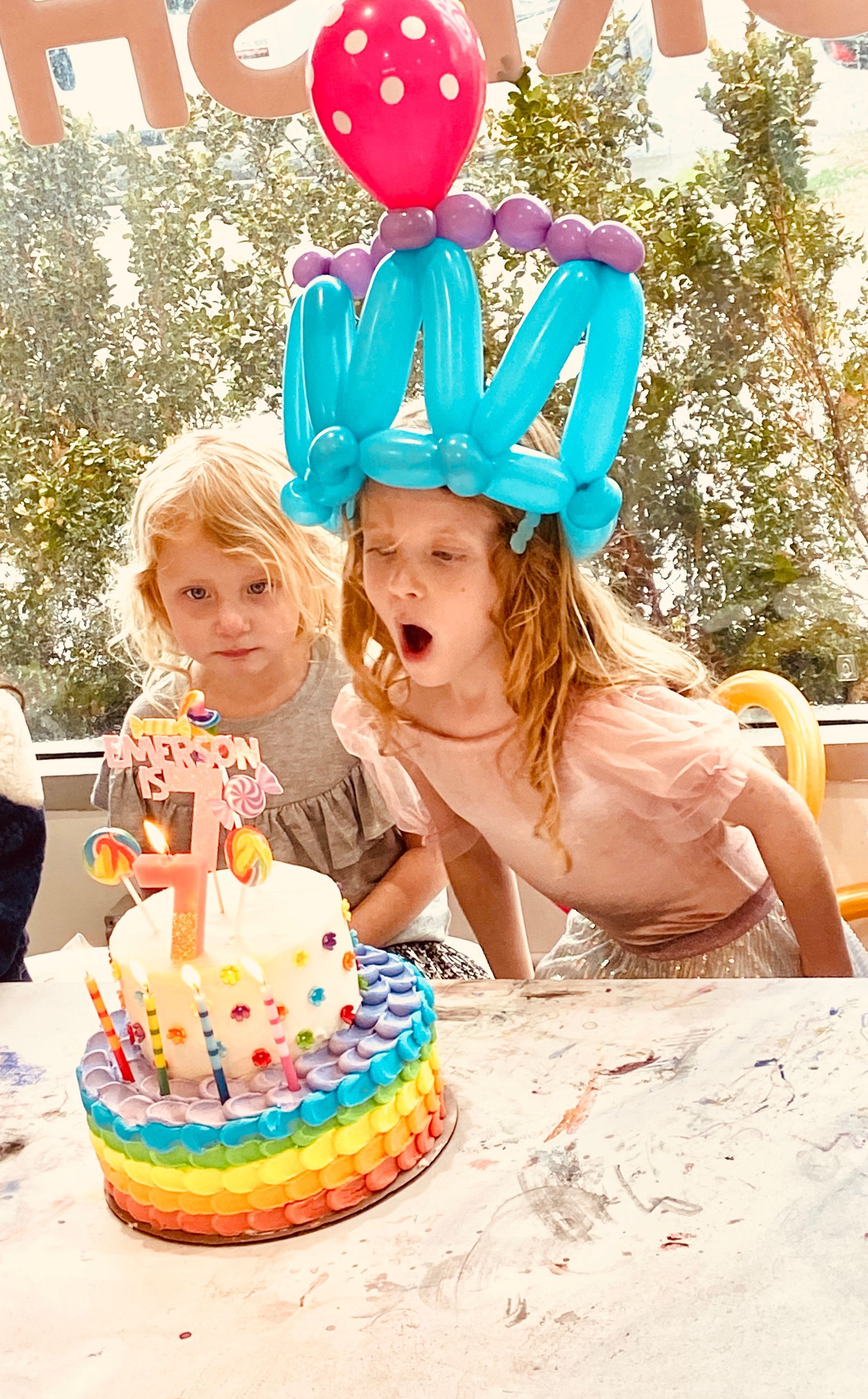 Two little girls are sitting at a table with a birthday cake.
