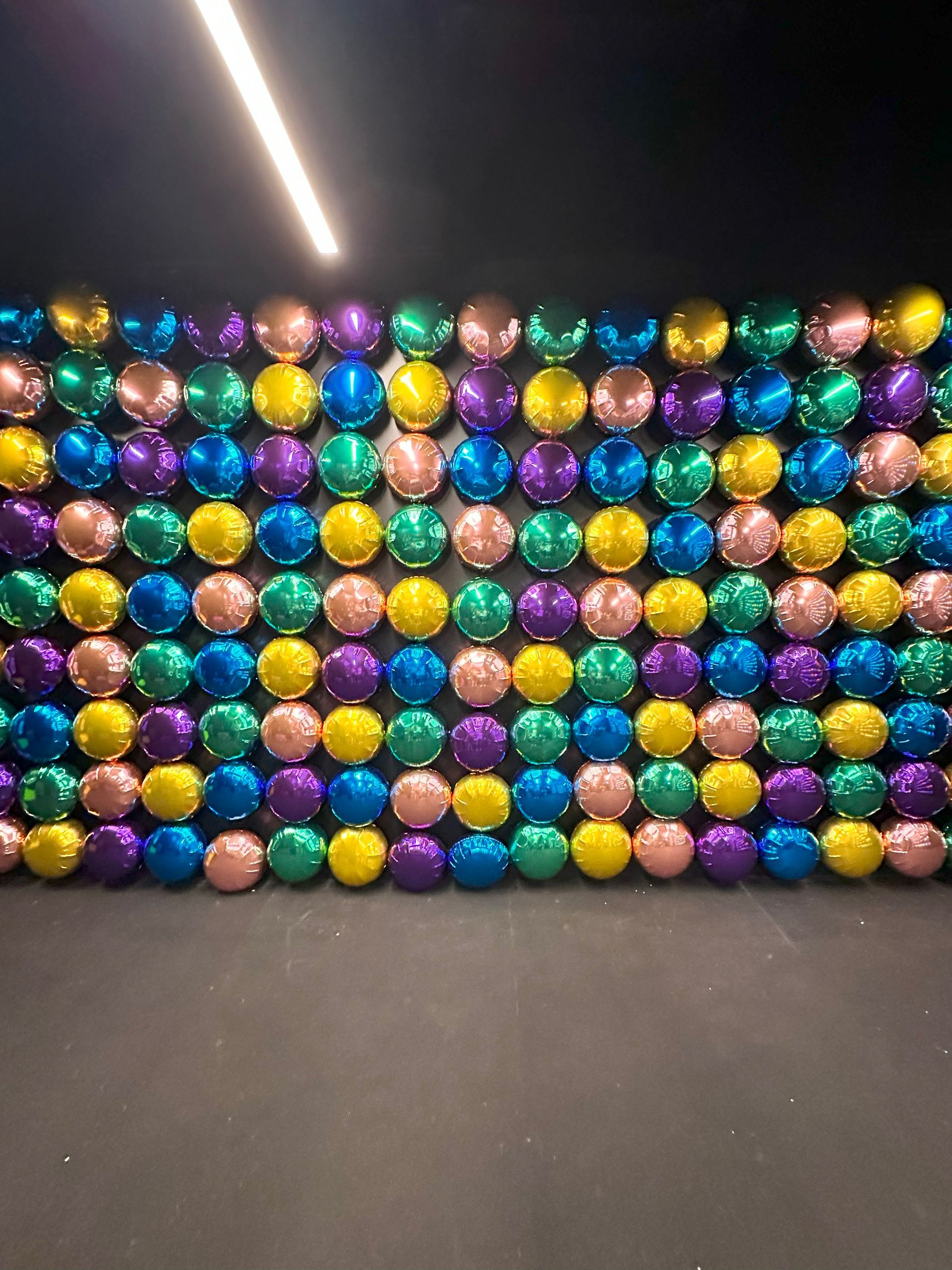A wall of colorful balloons in a dark room