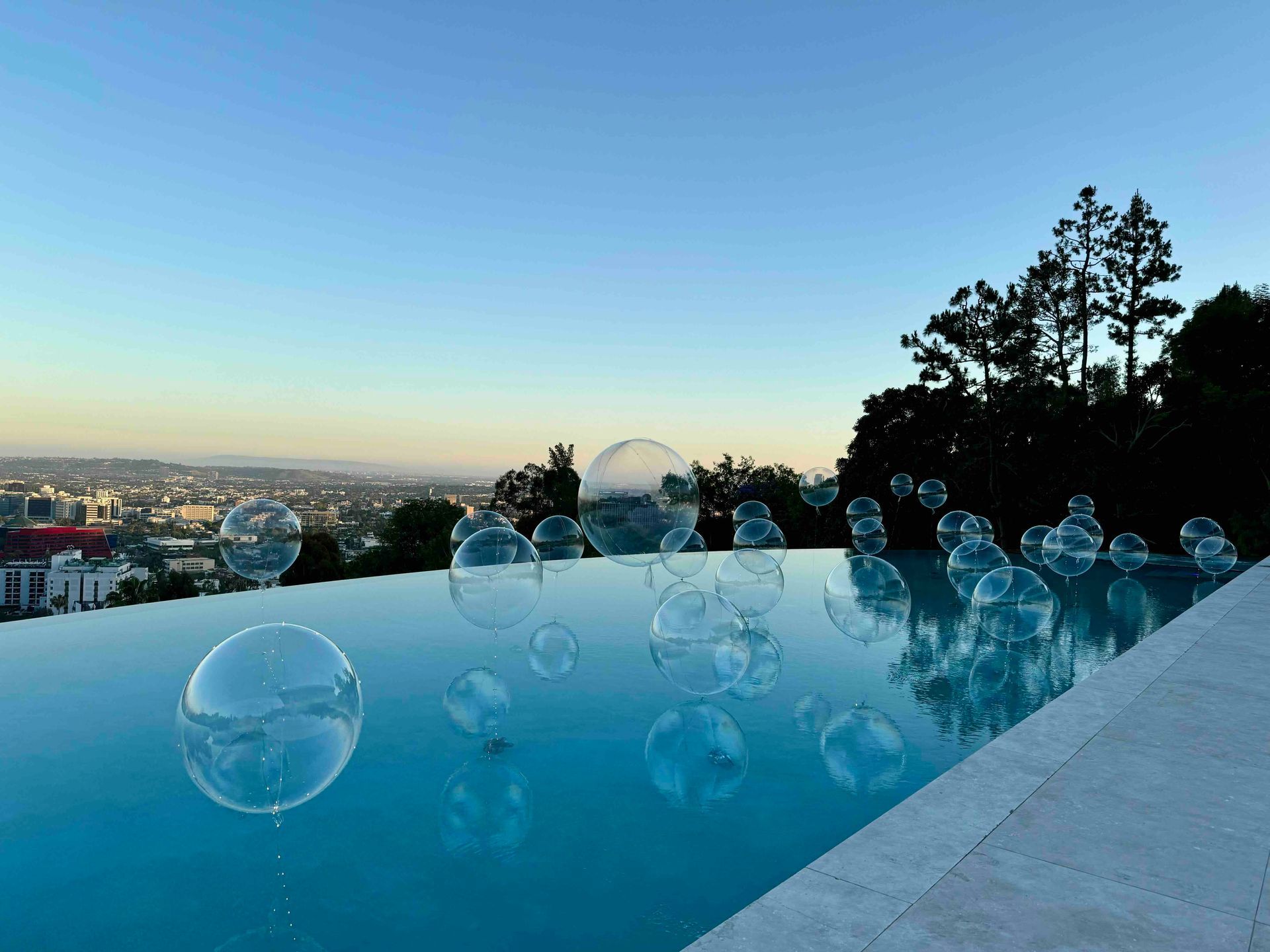 A swimming pool filled with bubble balloons and a view of a city.