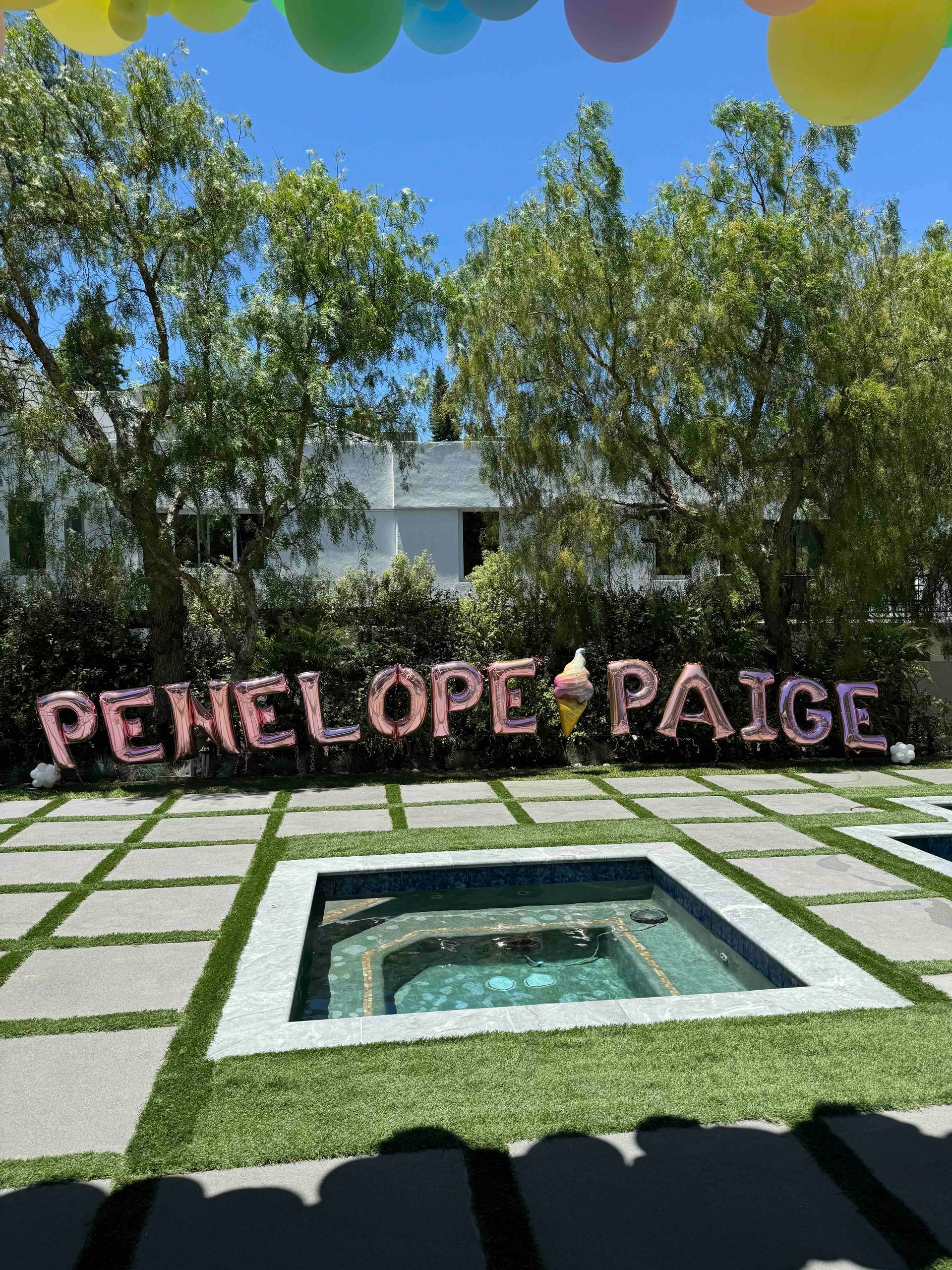 Penelope & Paige is written in balloons in front of a pool.