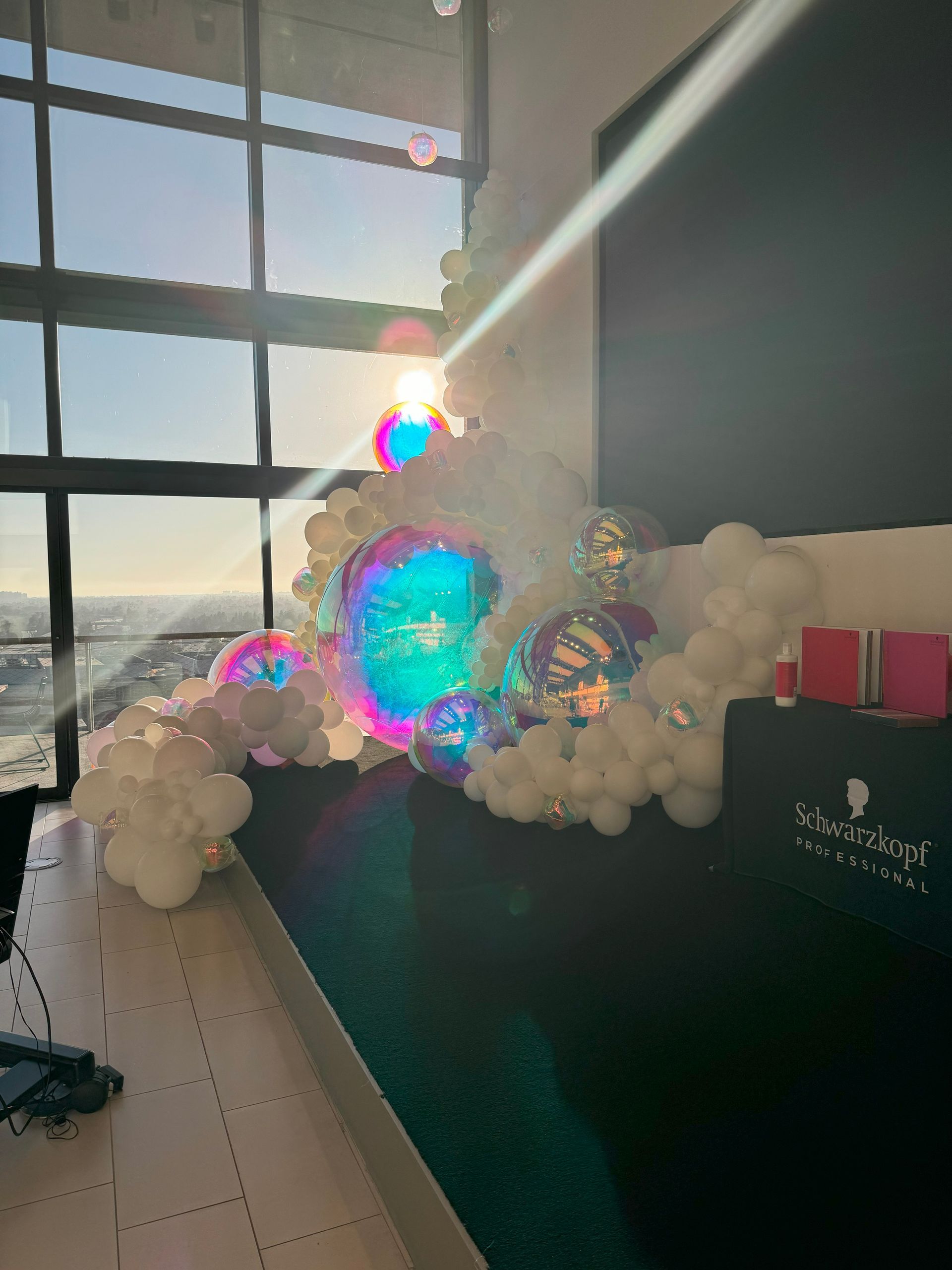 A room filled with balloons and gifts with the sun shining through the windows.