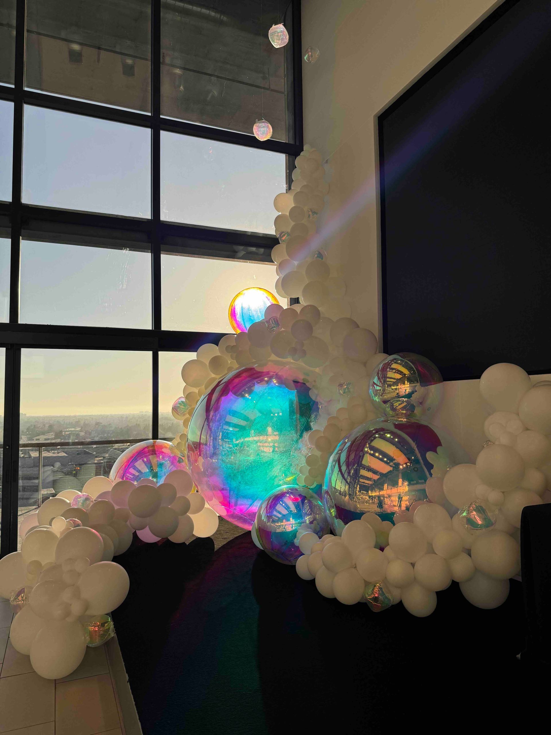 A bunch of balloons are sitting in front of a window.