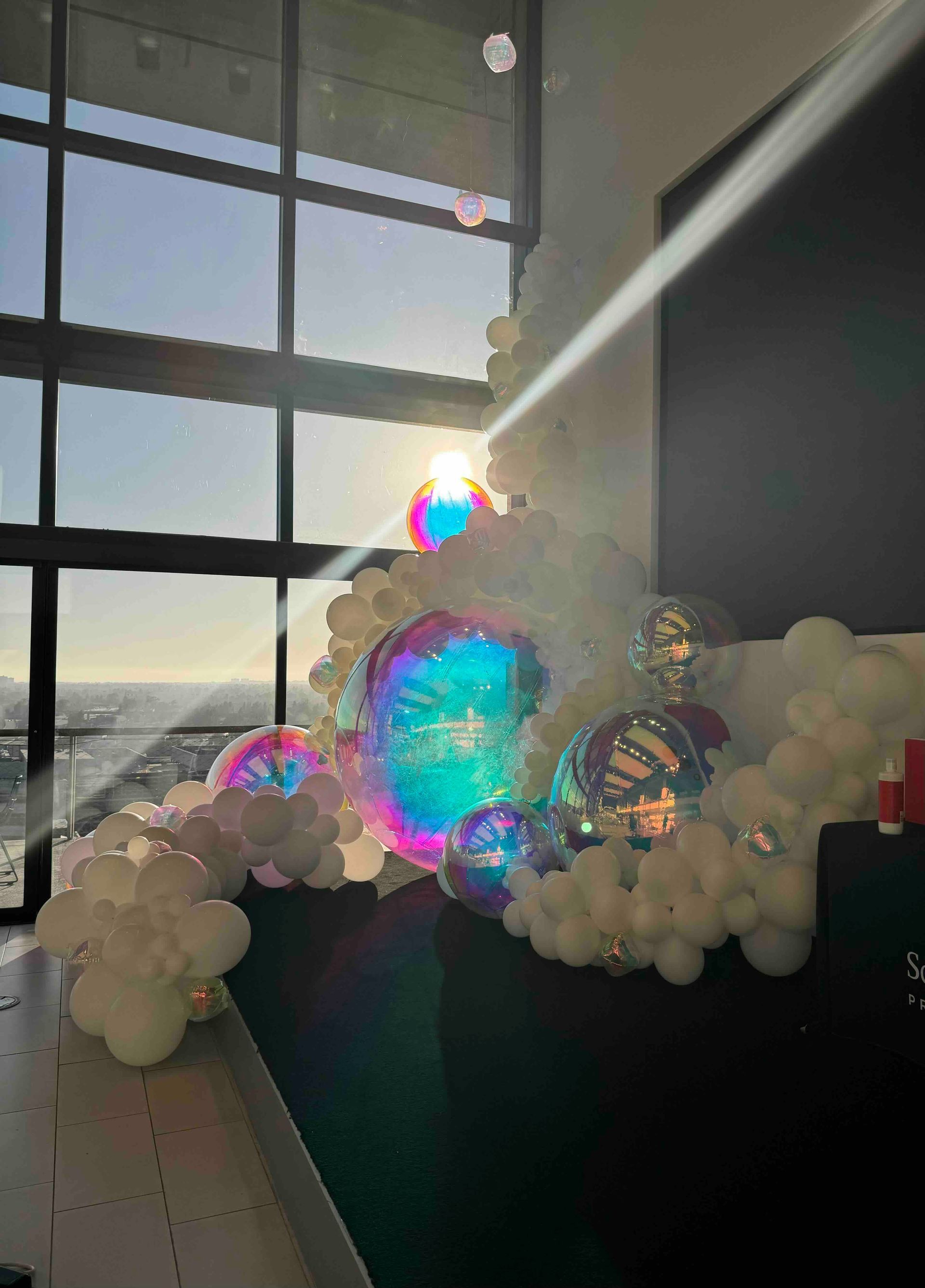 A bunch of balloons are sitting on a table in front of a window.