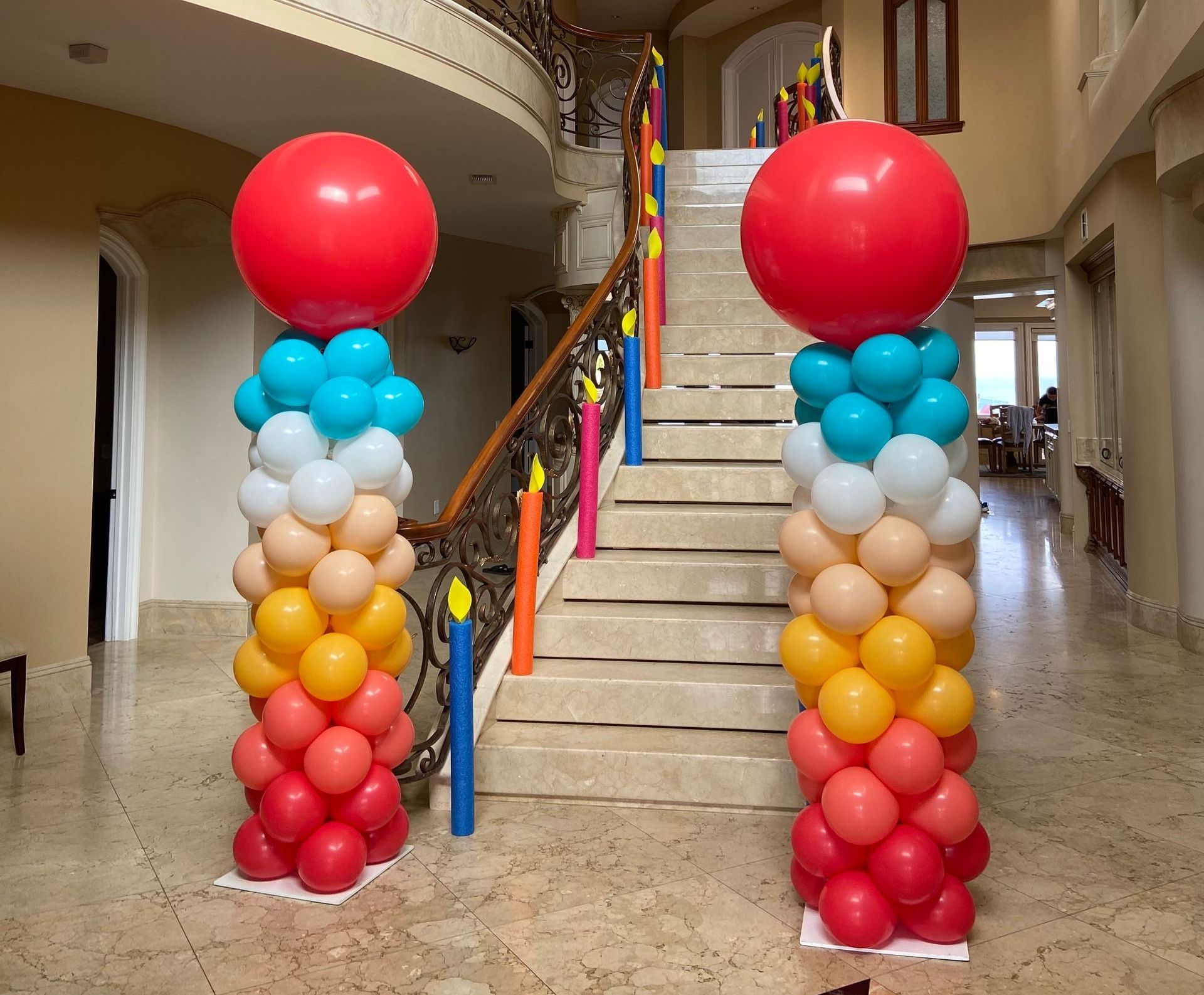 Two columns made of balloons are in front of a set of stairs.
