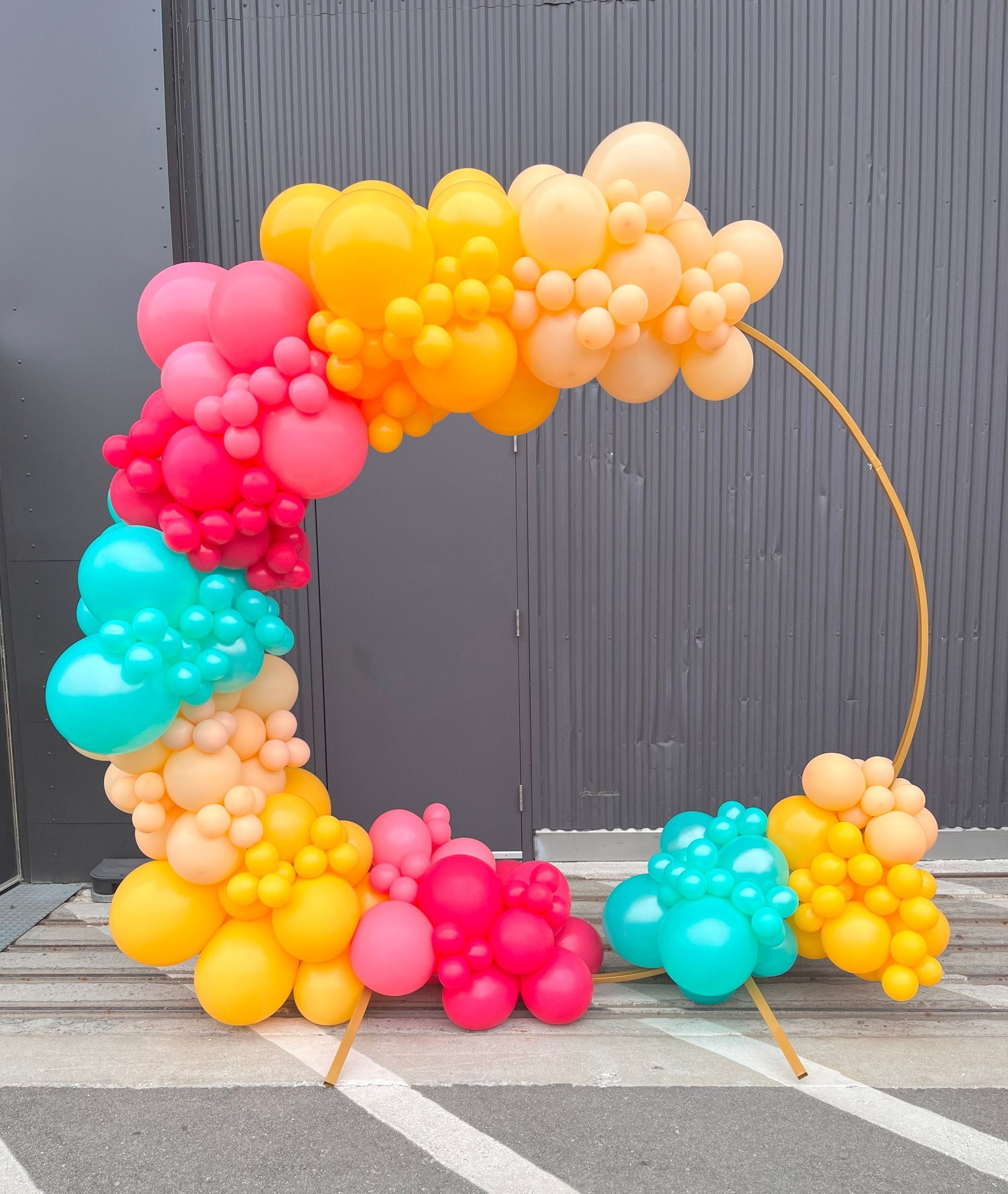 A bunch of colorful balloons are sitting on the ground in front of a building.