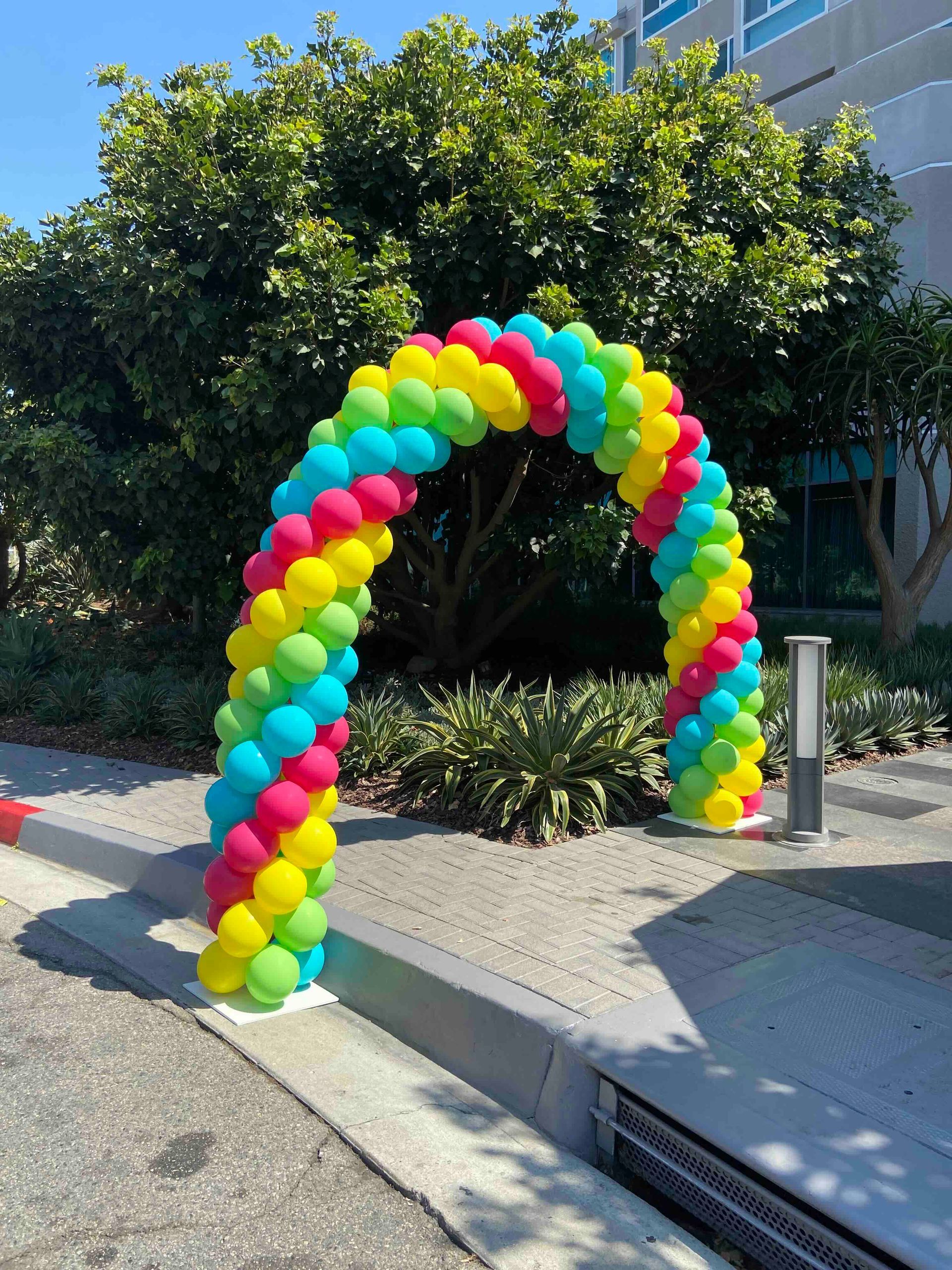 A colorful balloon arch is sitting on the side of the road.
