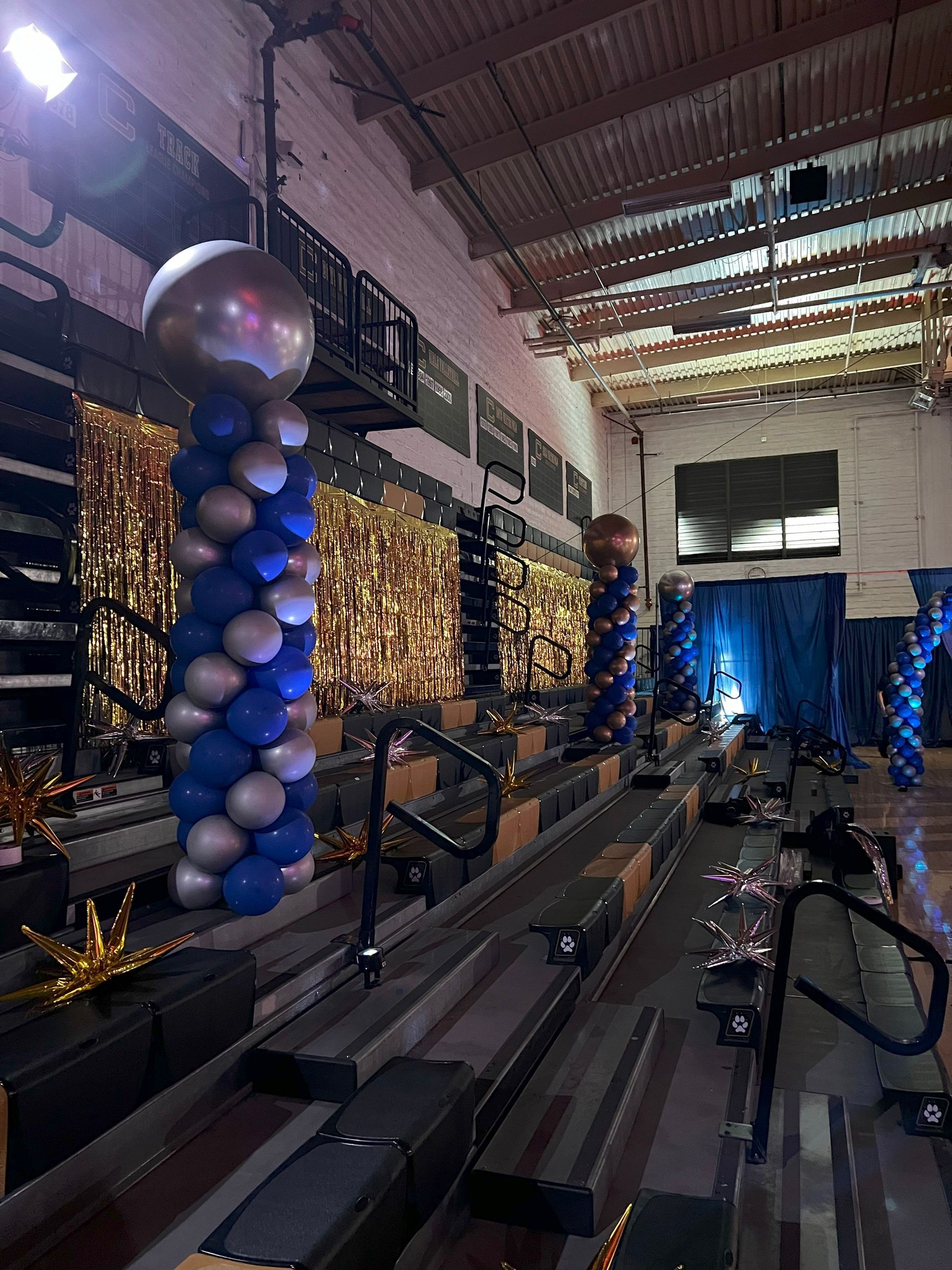 A stadium is decorated with blue and silver balloons for a graduation ceremony.