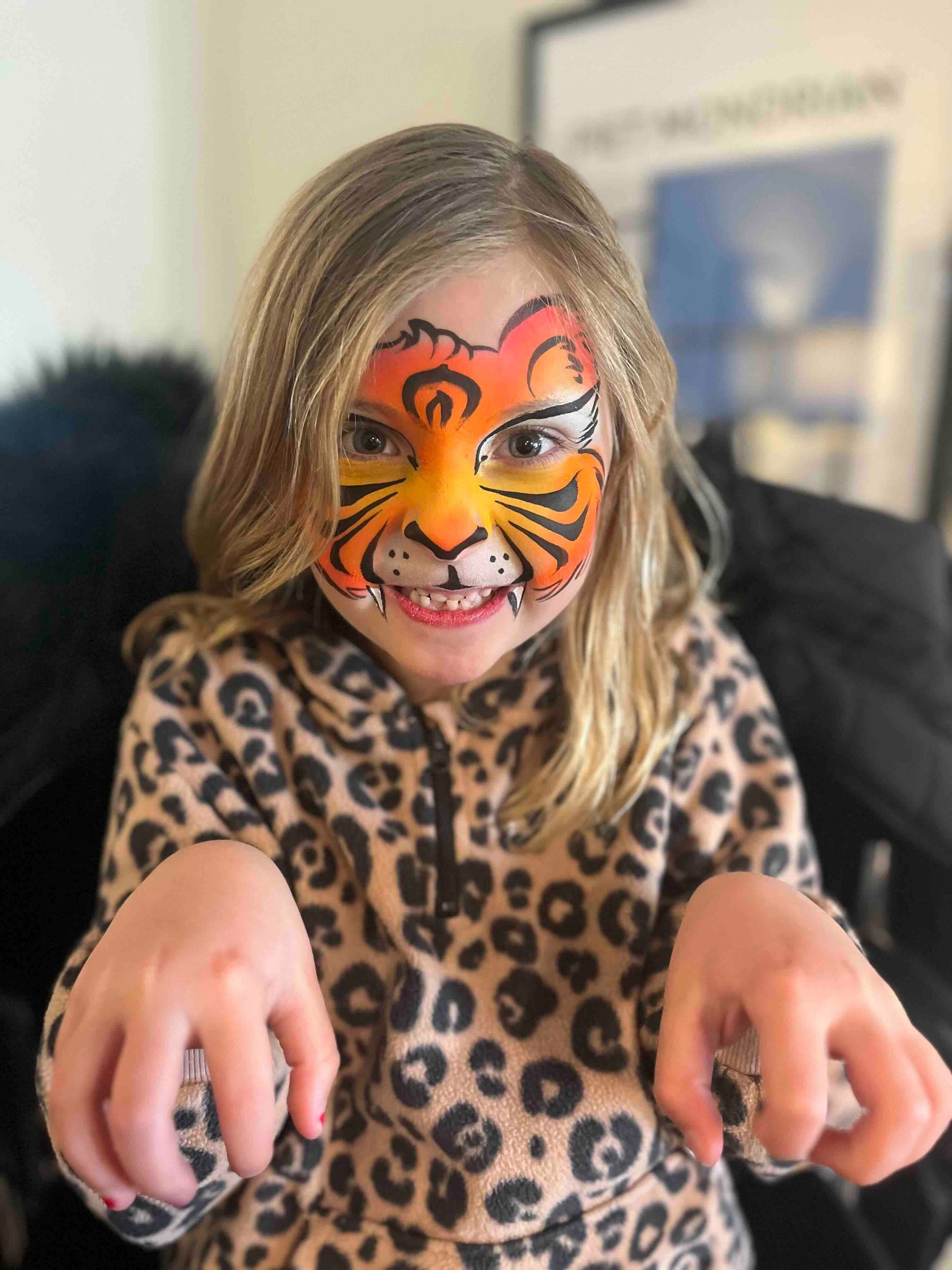 A little girl with her face painted like a tiger.