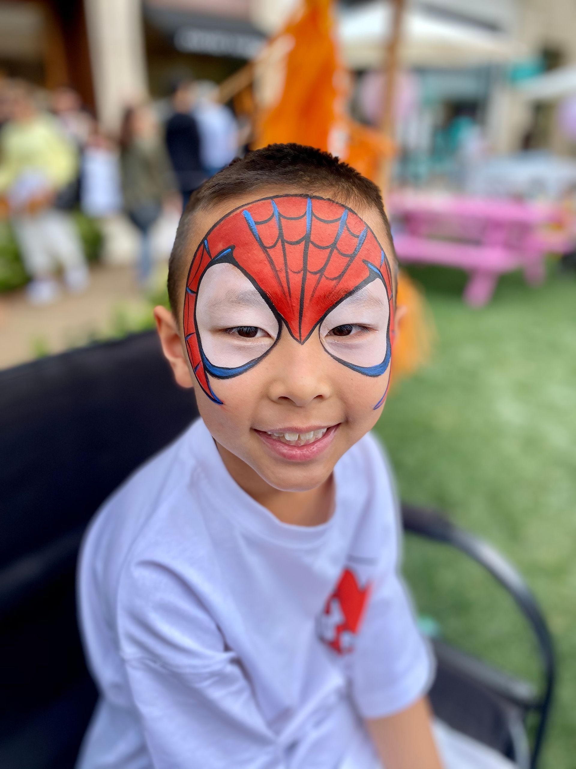 A young boy with a spider man face paint on his face.
