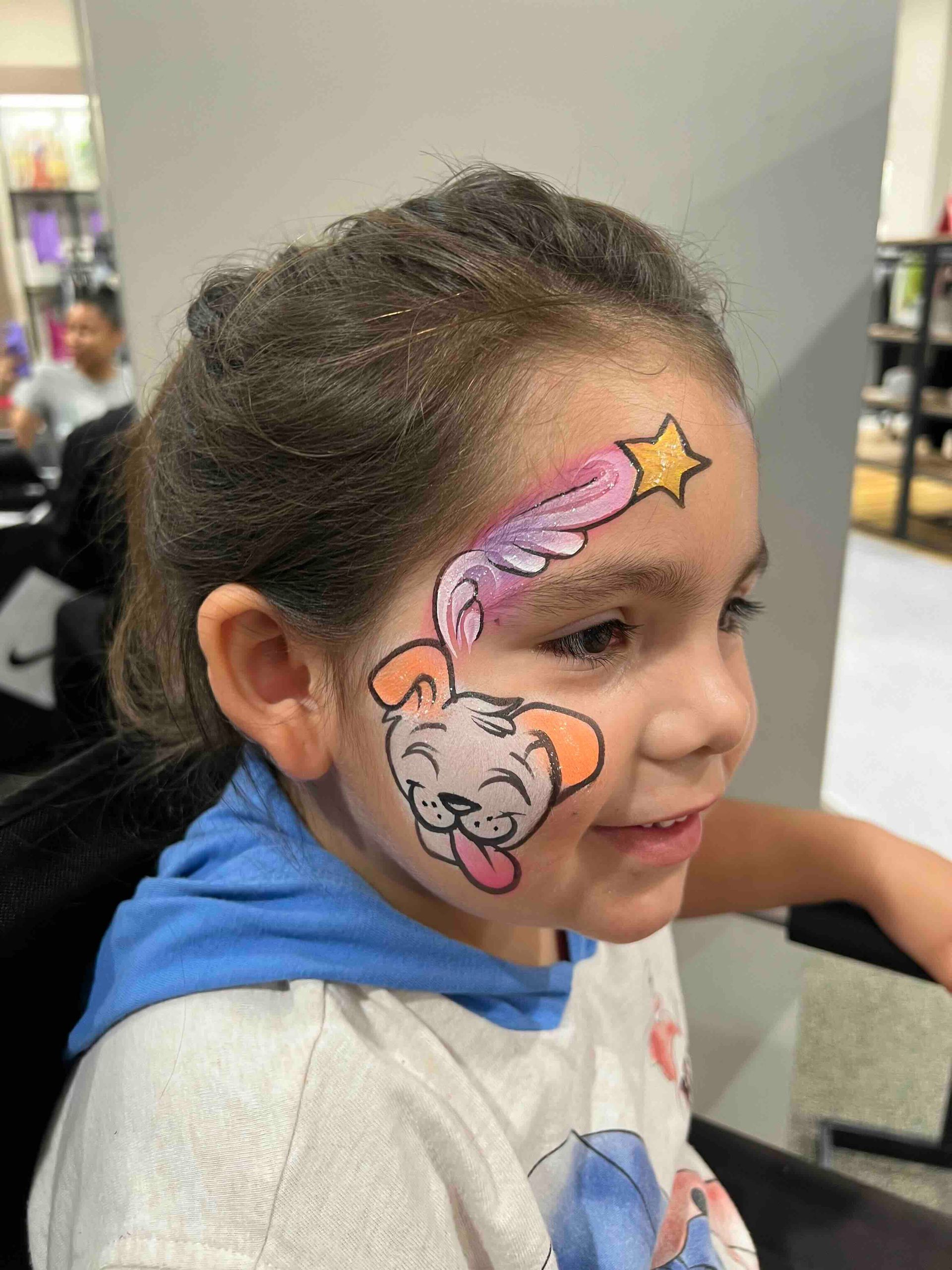 A little girl has her face painted with a dog and a star.