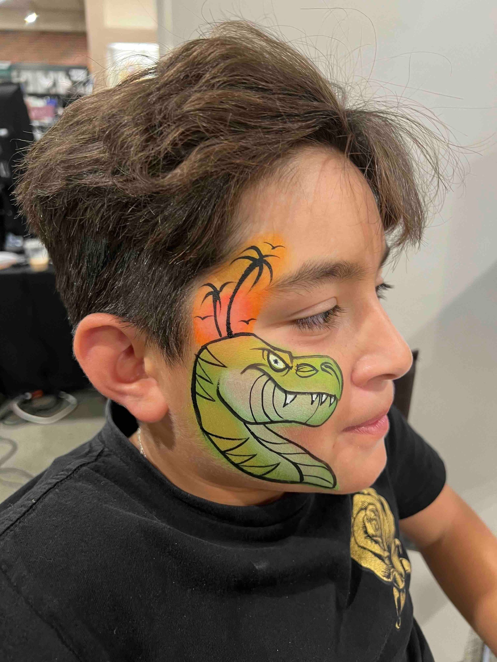 A young boy has his face painted like a dinosaur.