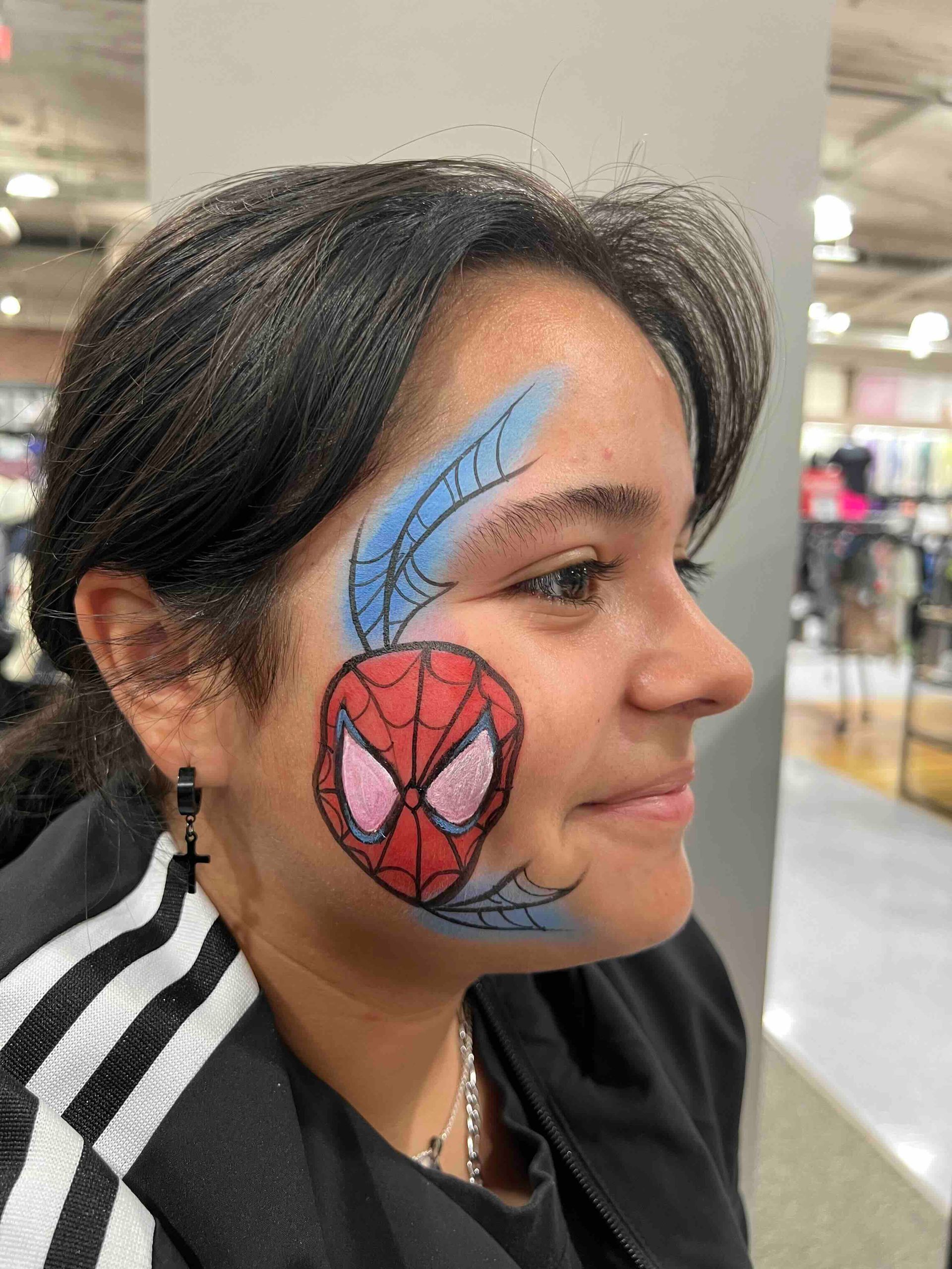 A woman has a spider man face painted on her face.