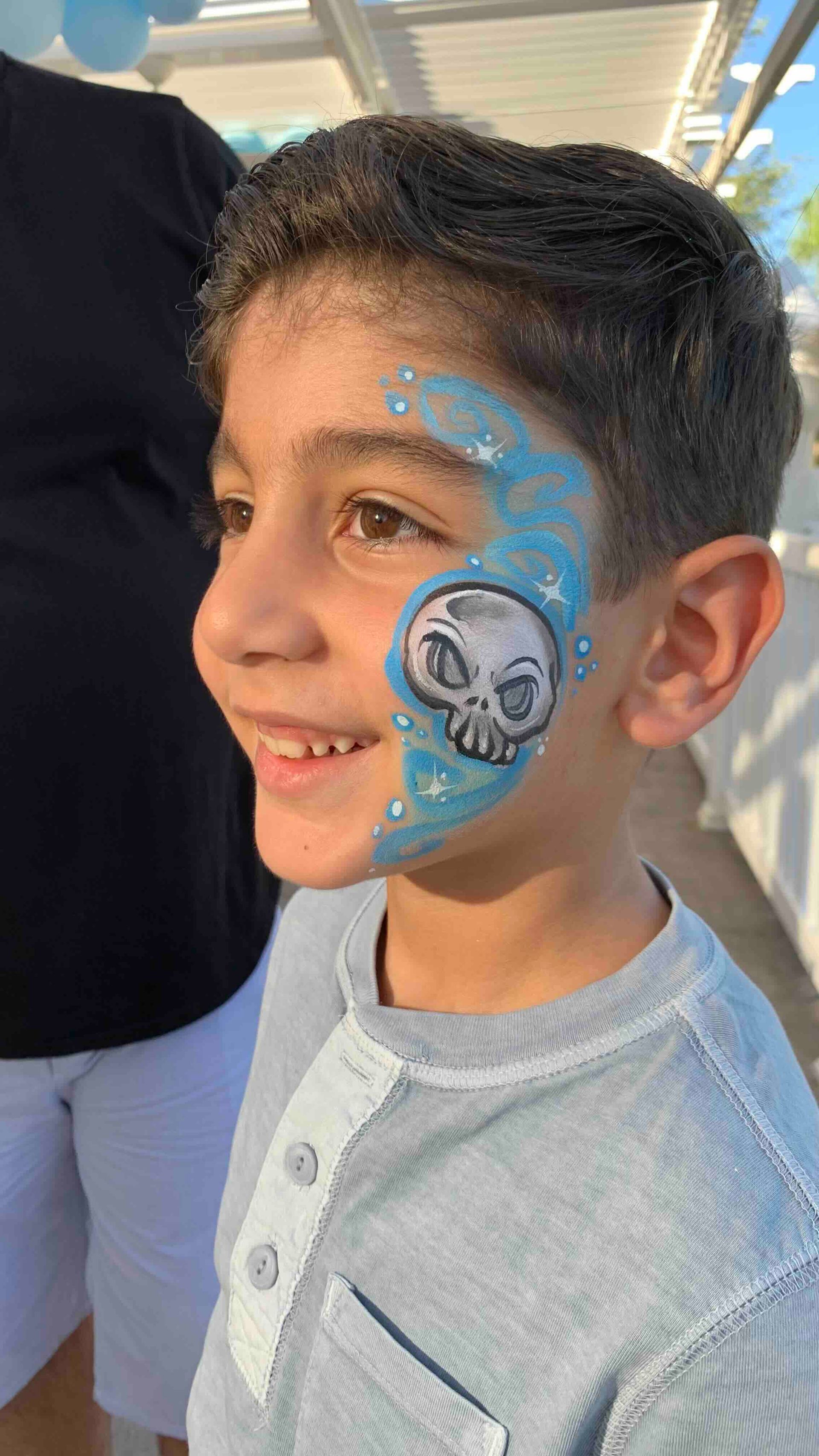 A young boy with a skull painted on his face.