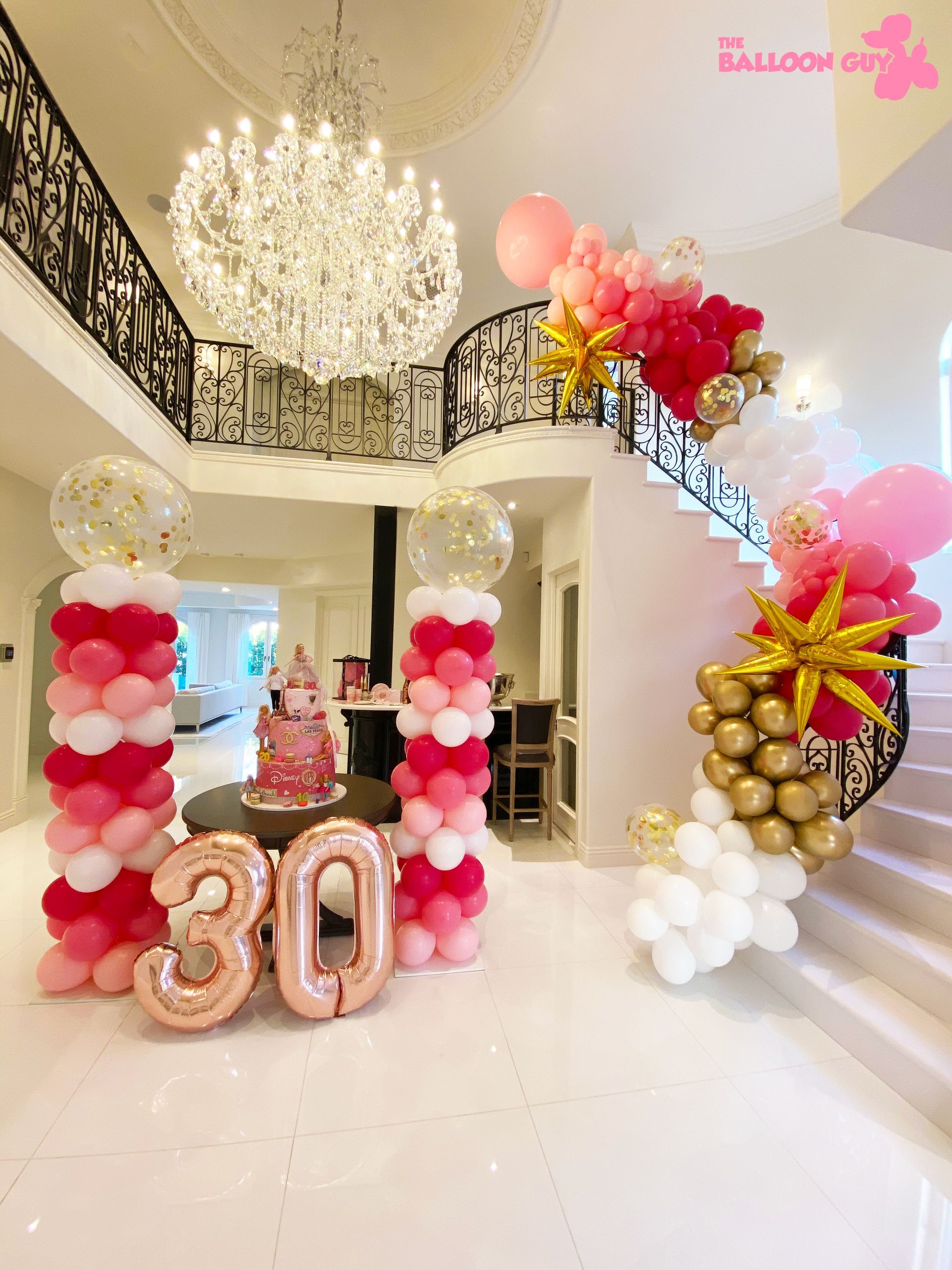 A room filled with balloons and a cake with the number 30 on it.
