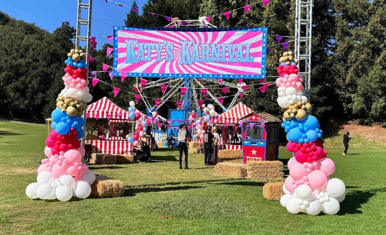 A ferris wheel is decorated with balloons and popcorn at a carnival.