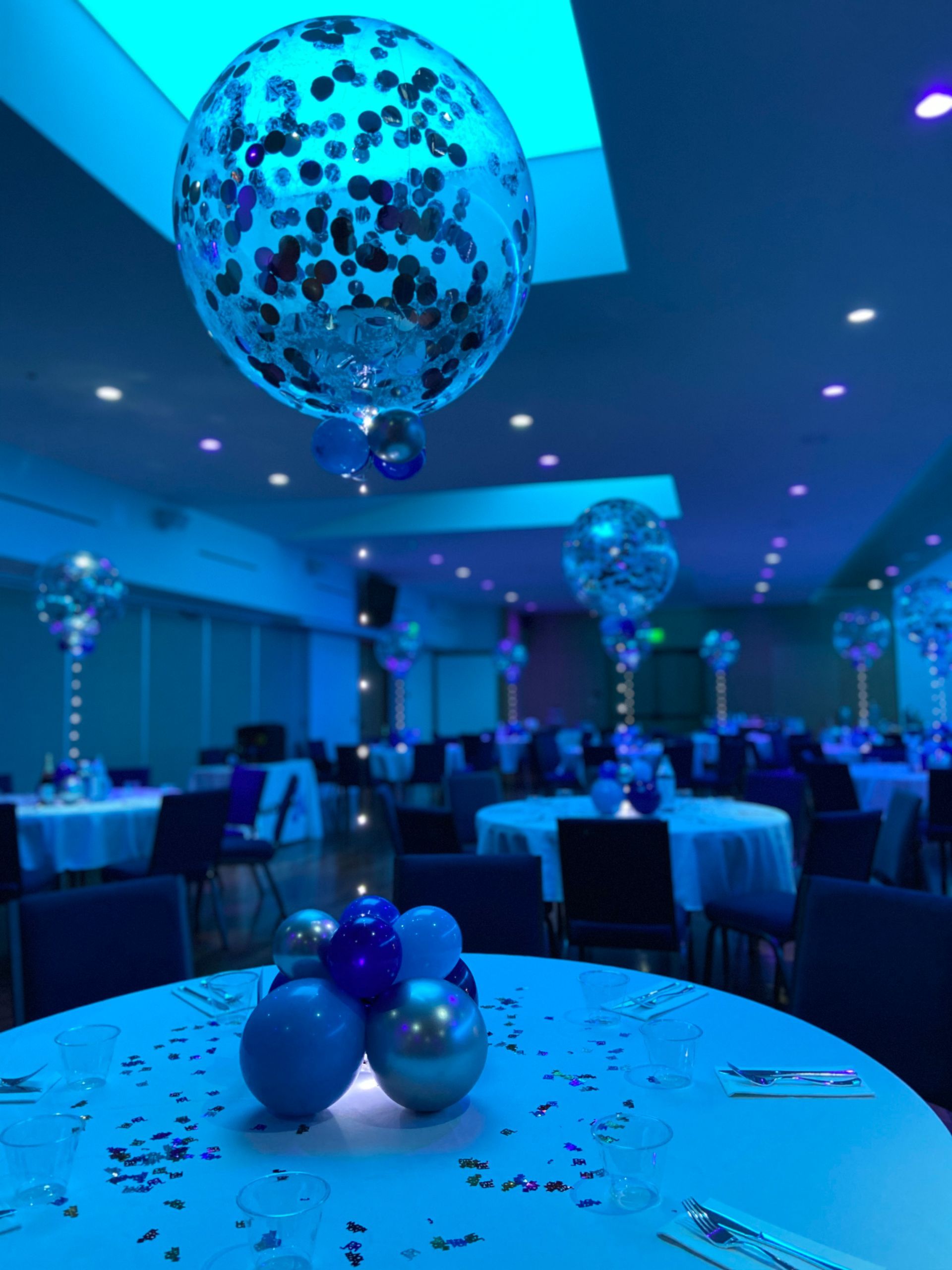 A room with tables and chairs and balloons on them