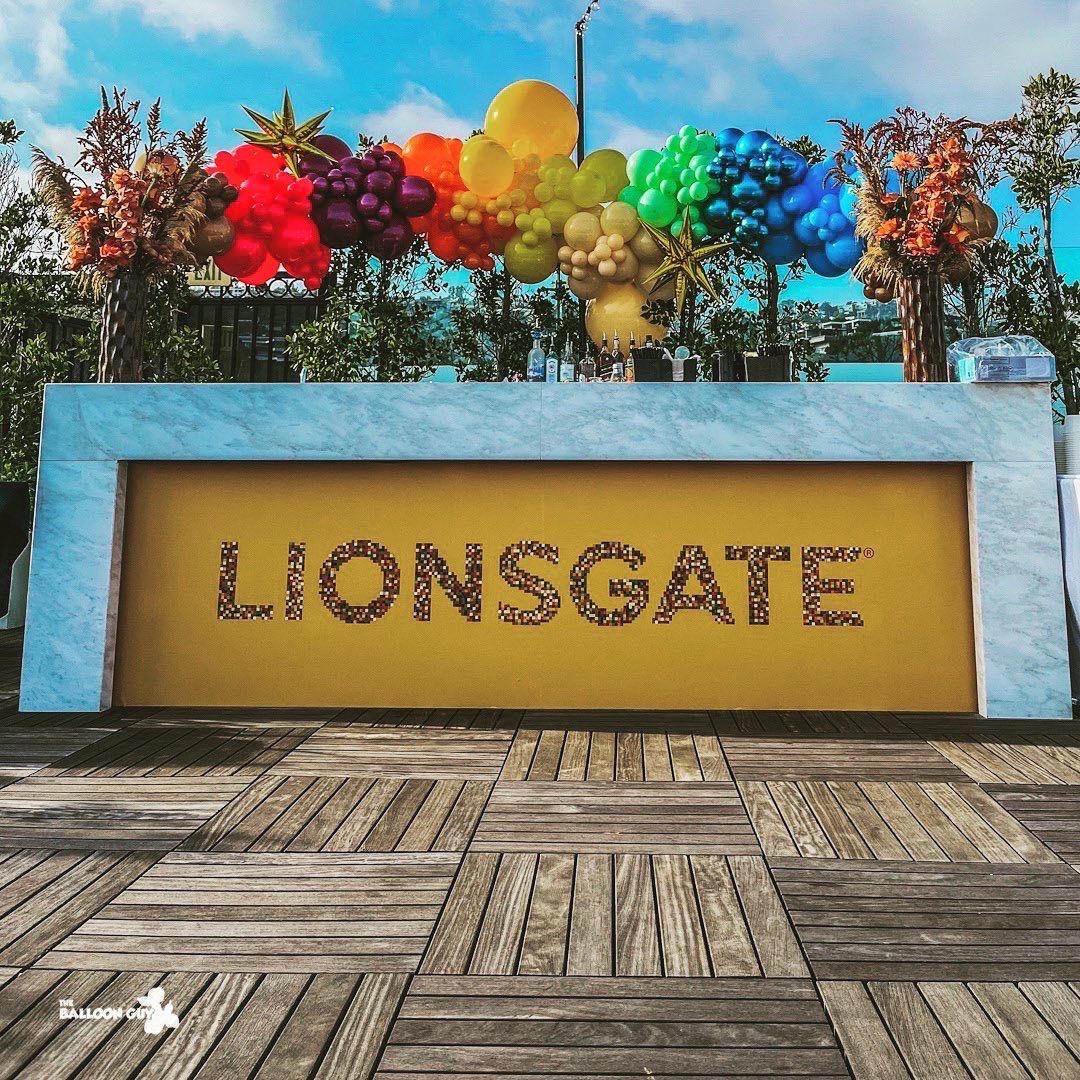 A sign that says lionsgate is surrounded by balloons and flowers.