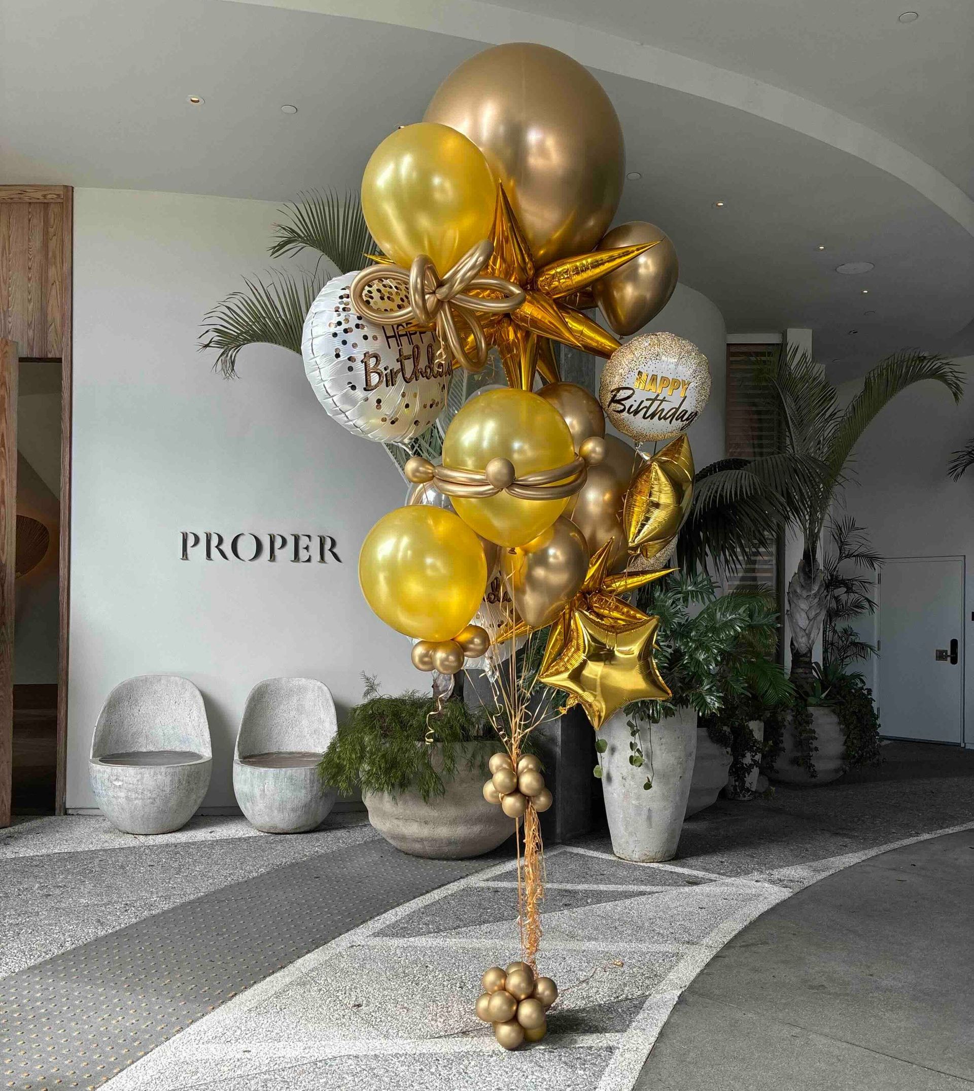 A bunch of gold balloons are sitting on the floor in a room.