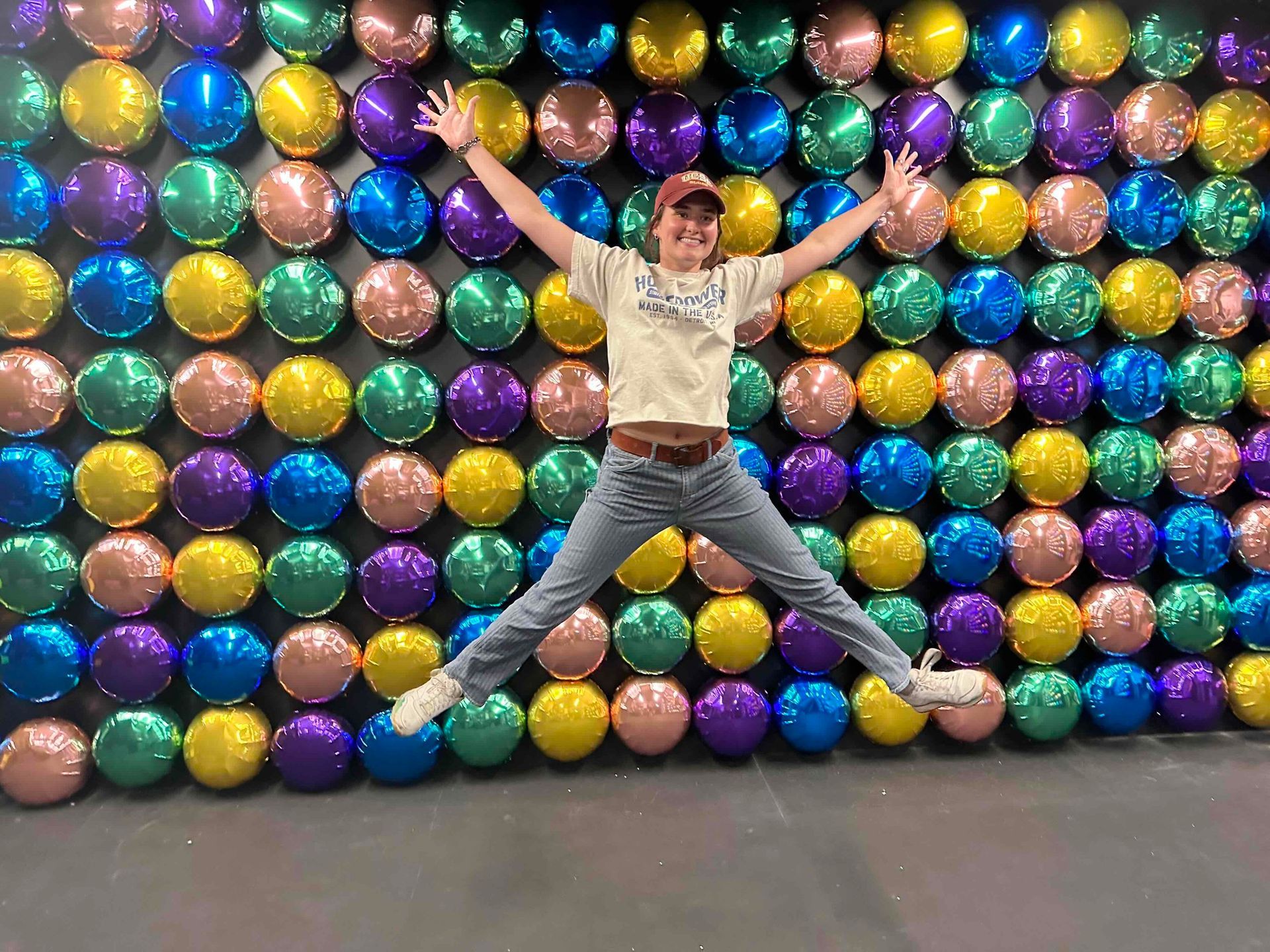 A person is jumping in front of a wall of balloons.