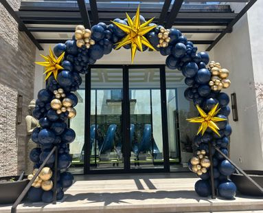 A blue and gold balloon arch is in front of a building.