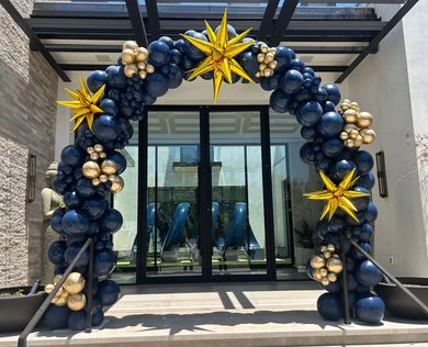 A blue and gold balloon arch is in front of a building.