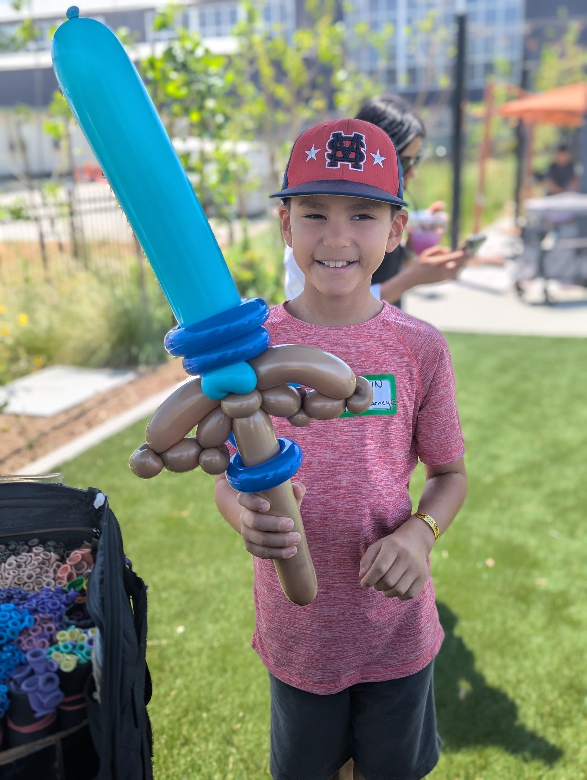 A little boy holding a sword made of balloons.