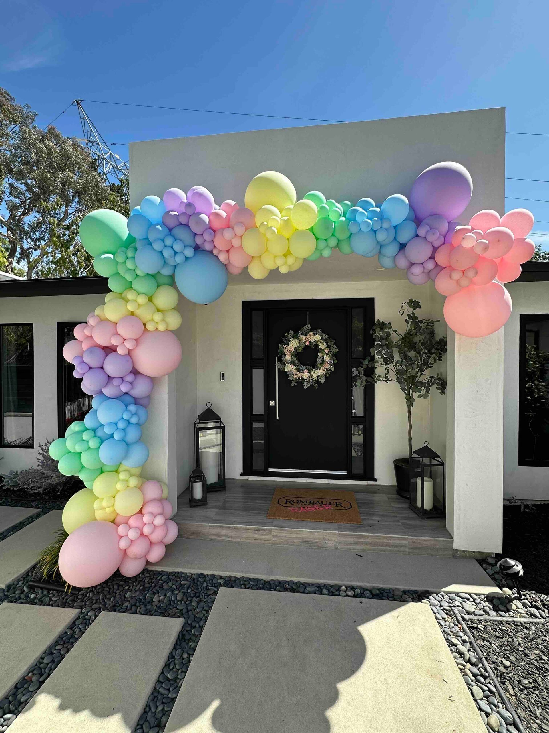 A house with a rainbow of balloons in front of it.