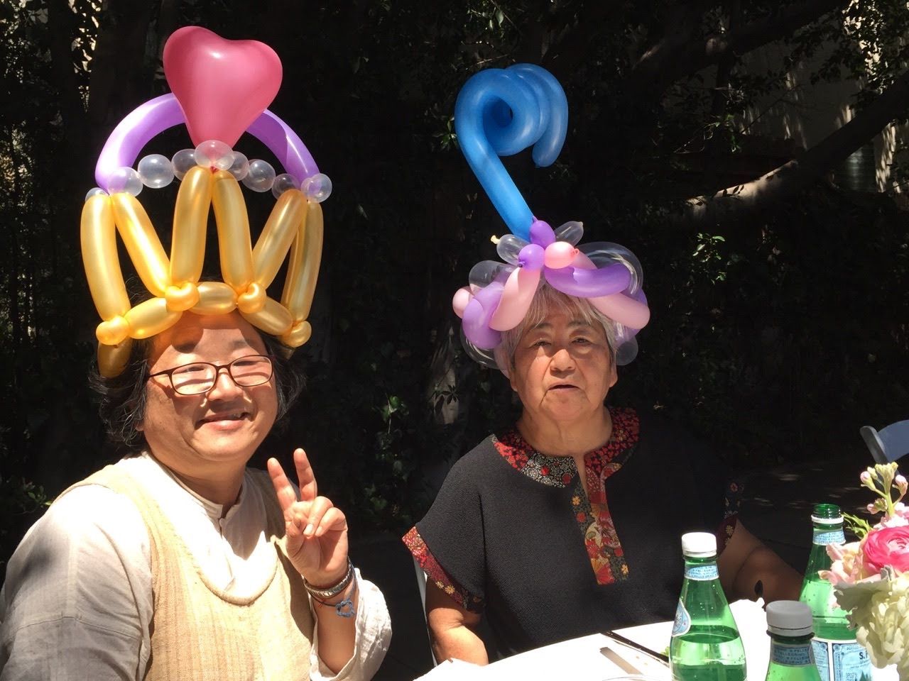Two women wearing balloon hats are sitting at a table