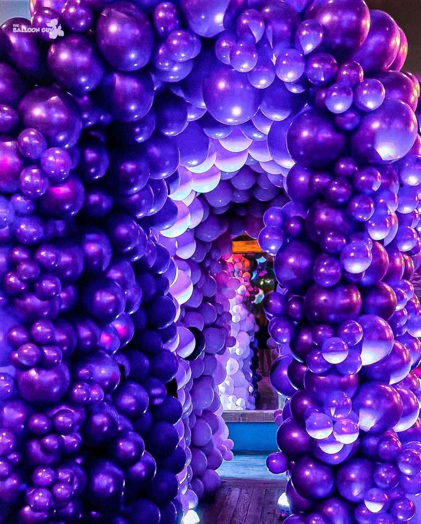 A bunch of purple balloons are stacked on top of each other.