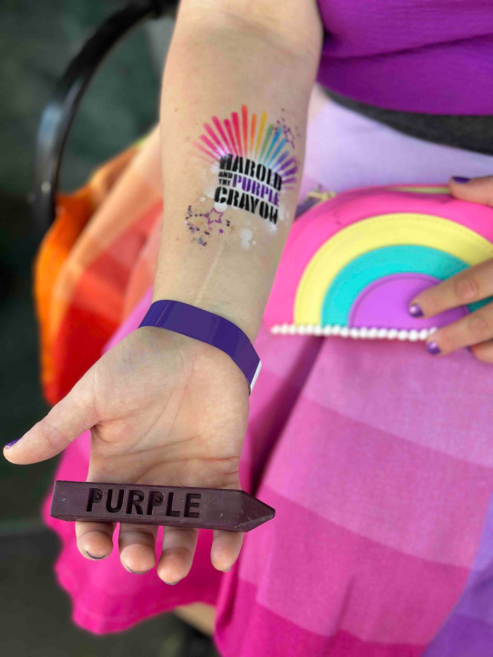 A person holding a purple stick on their wrist
