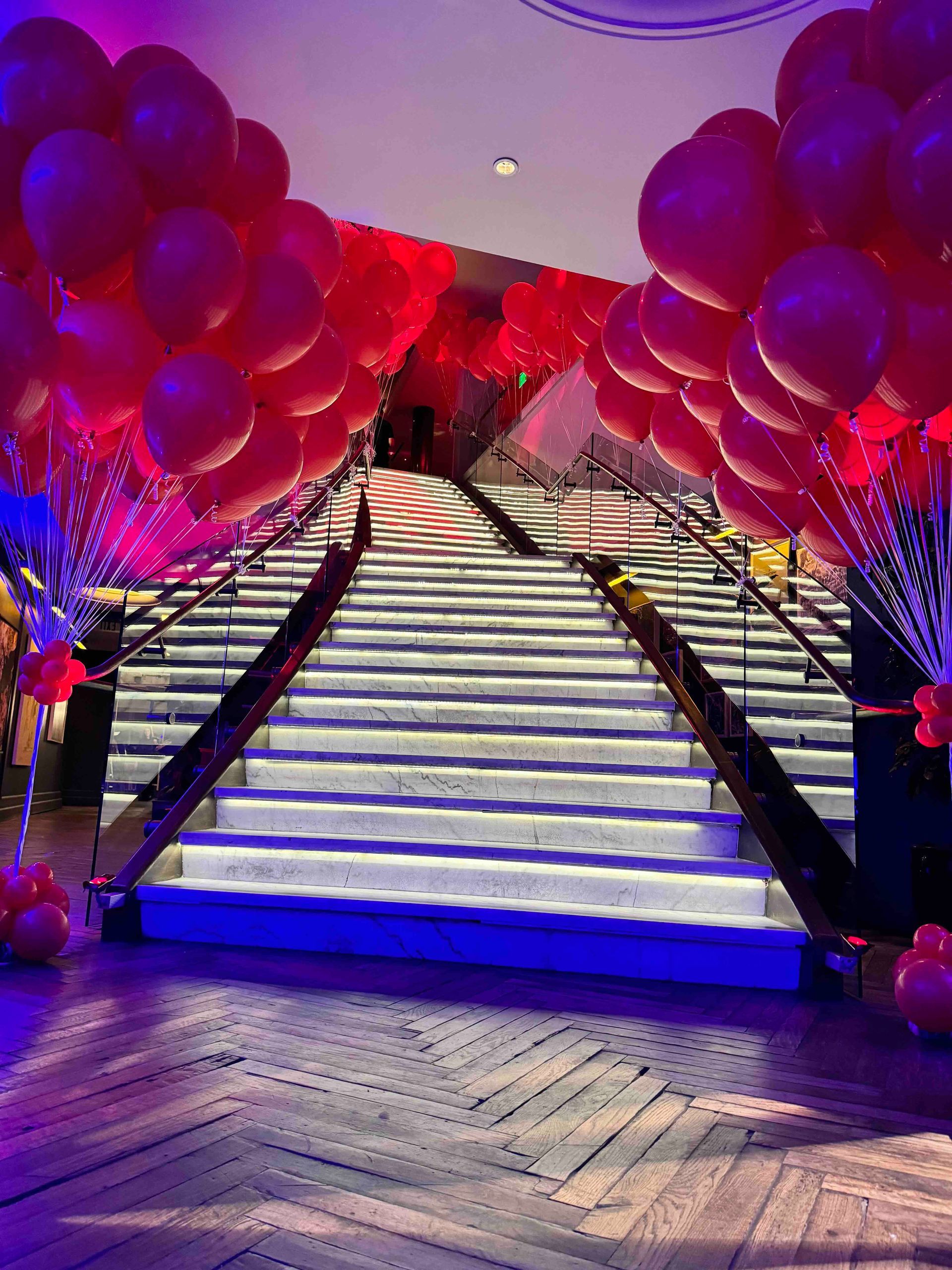 A bunch of red balloons are sitting on top of a set of stairs.
