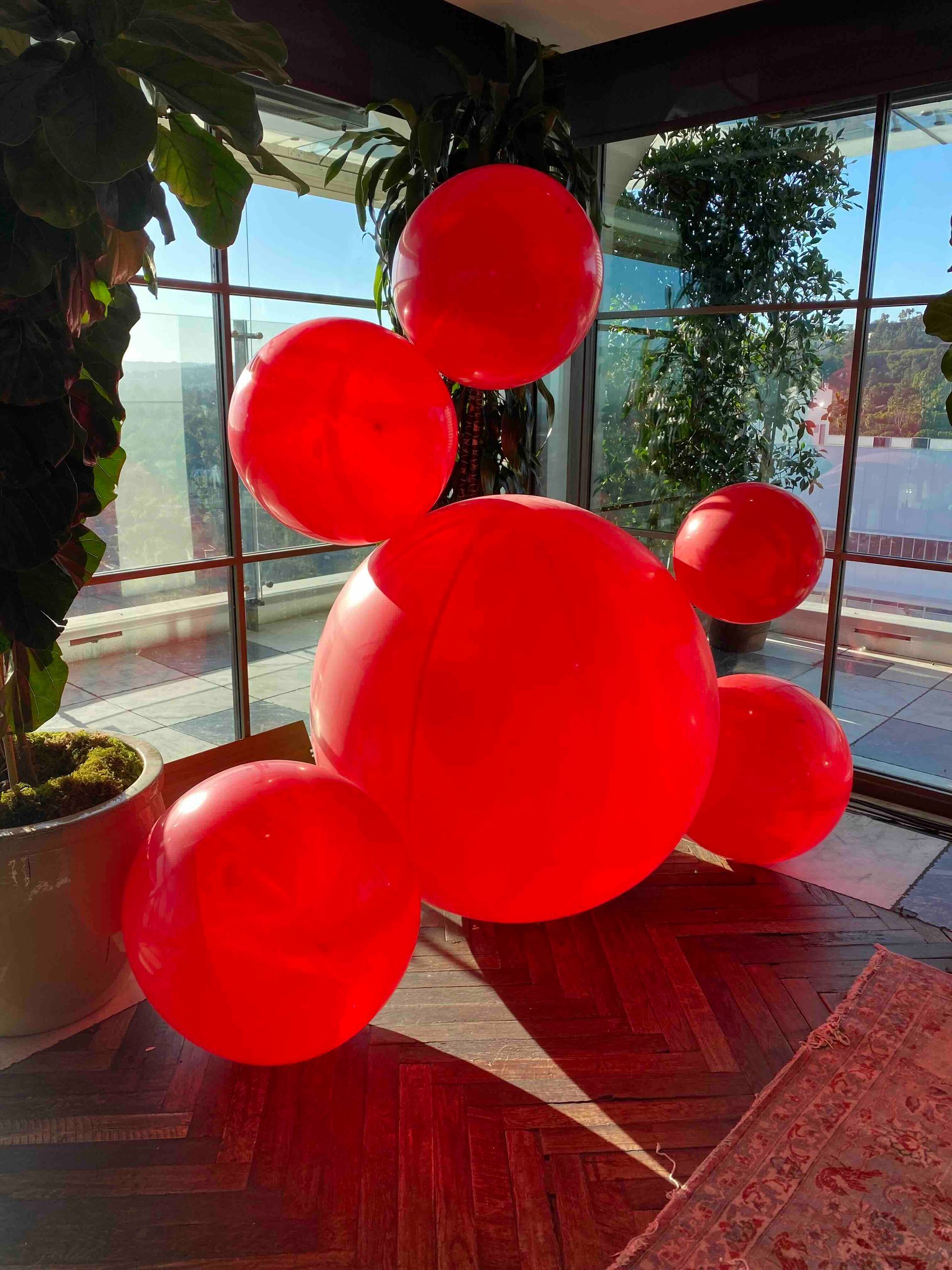 A bunch of red balloons are sitting on the floor in a room.