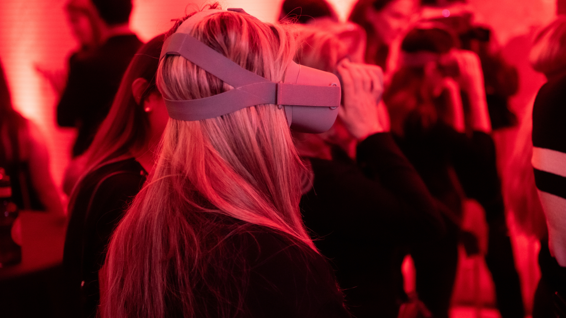 A woman is wearing a virtual reality headset in a crowd of people.