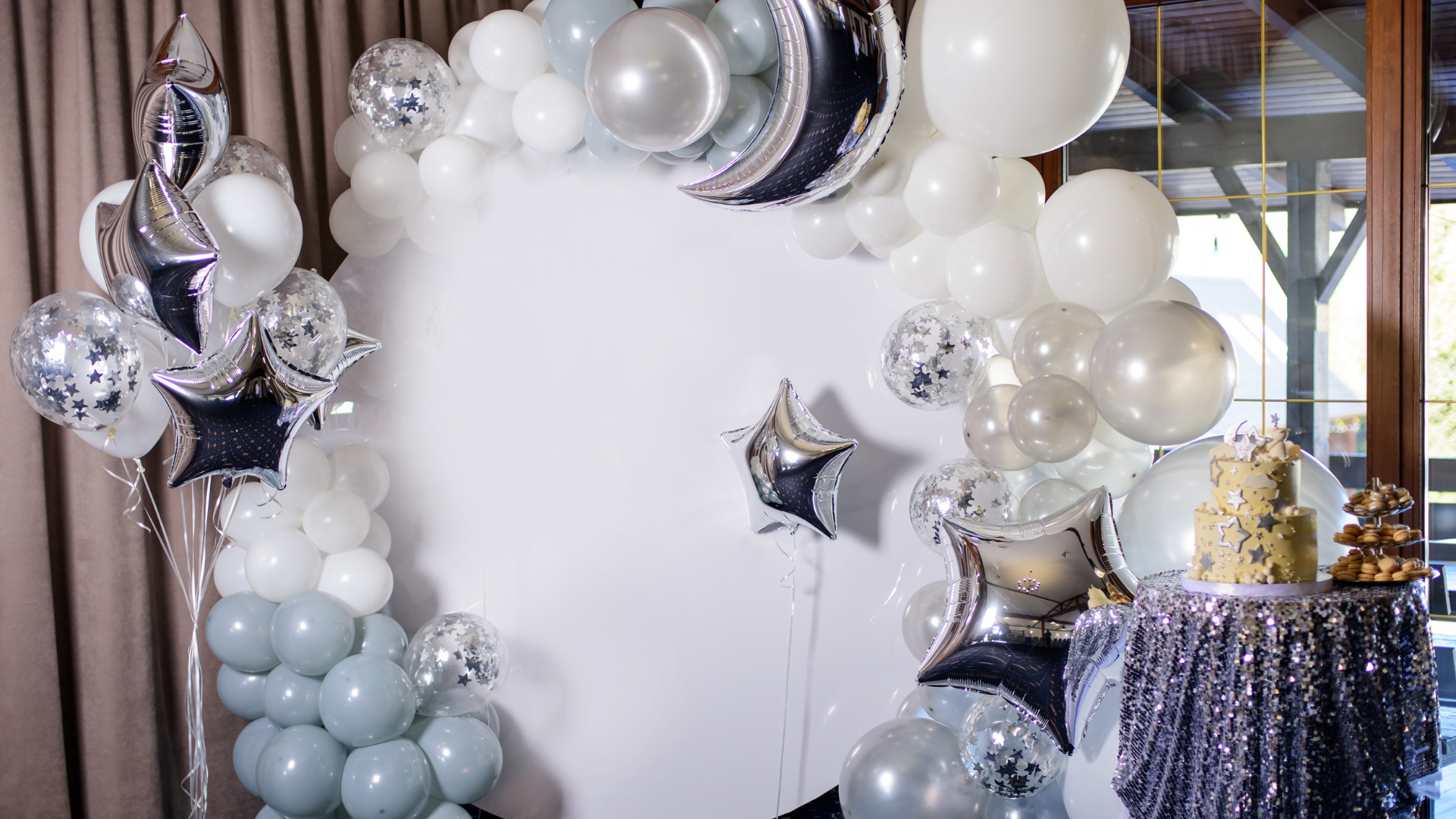 A room decorated with balloons and a cake on a table.