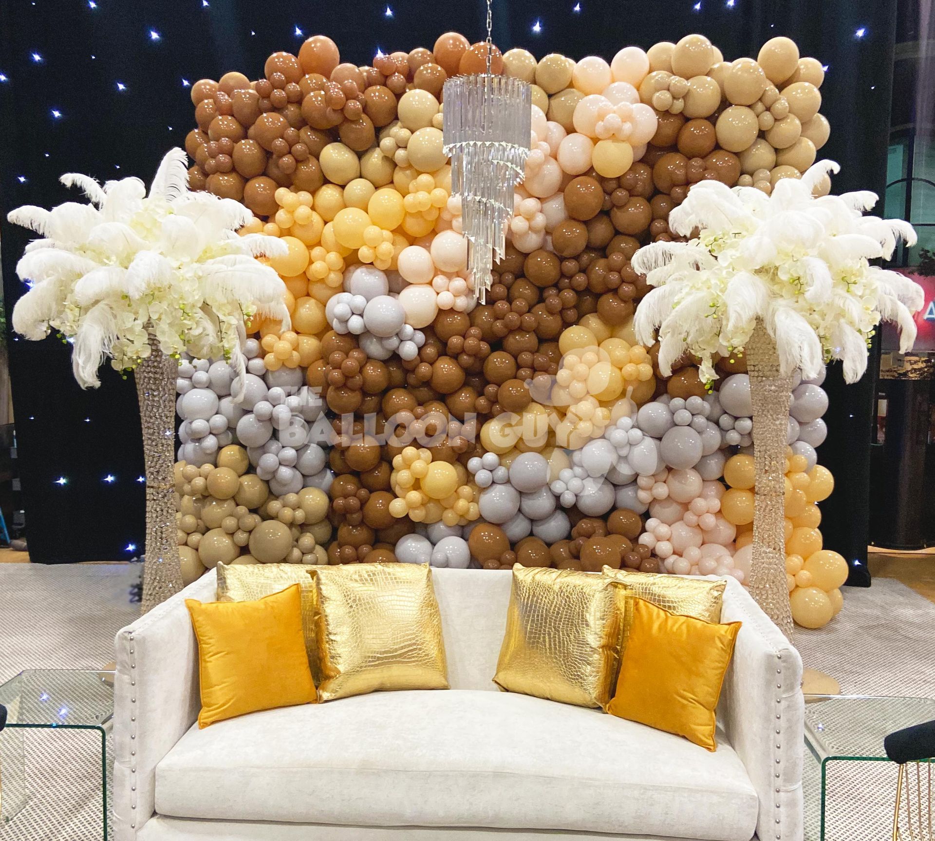 A couch is in front of a wall of balloons