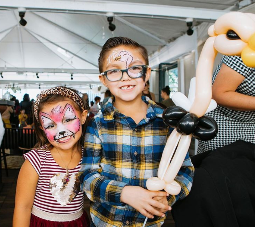 A boy and a girl with balloons and face paint